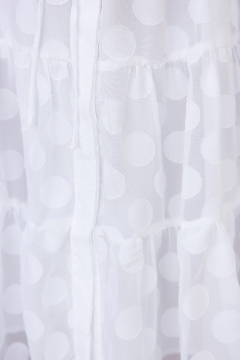Close-up of the Leylah Dress featuring textured white polka dot fabric and button-up front details.