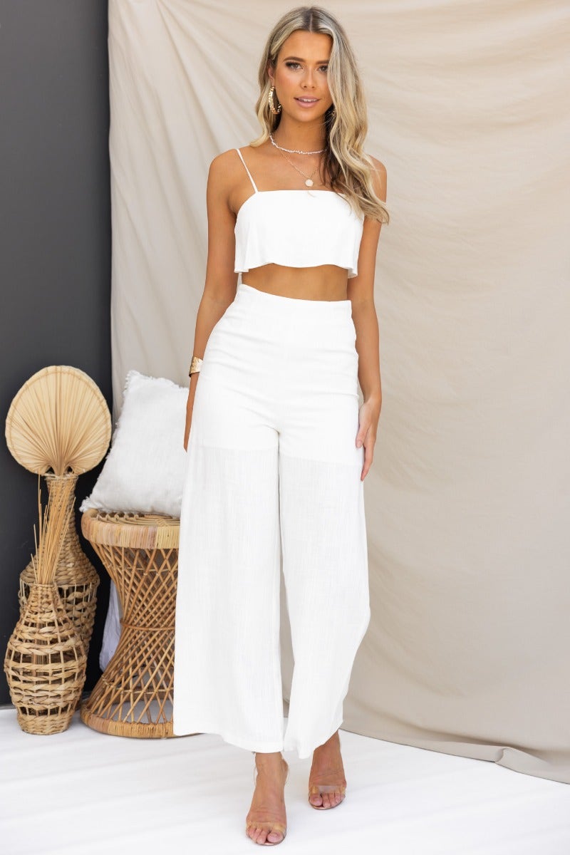 Model wearing Reed Pants, white linen blend, mid-high waist with relaxed fit, paired with a cropped top against a light backdrop.