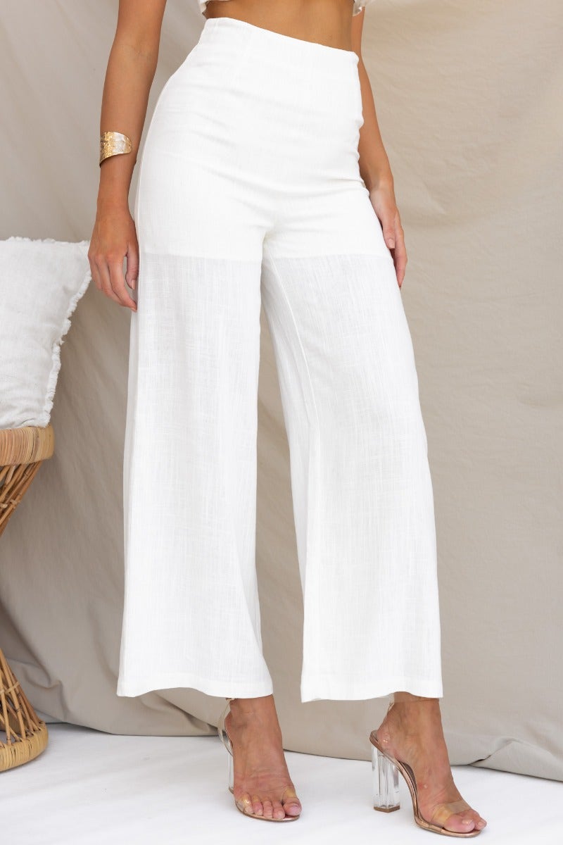 Stylish white Reed pants made from a linen blend, featuring a mid-high waist and a relaxed fit.