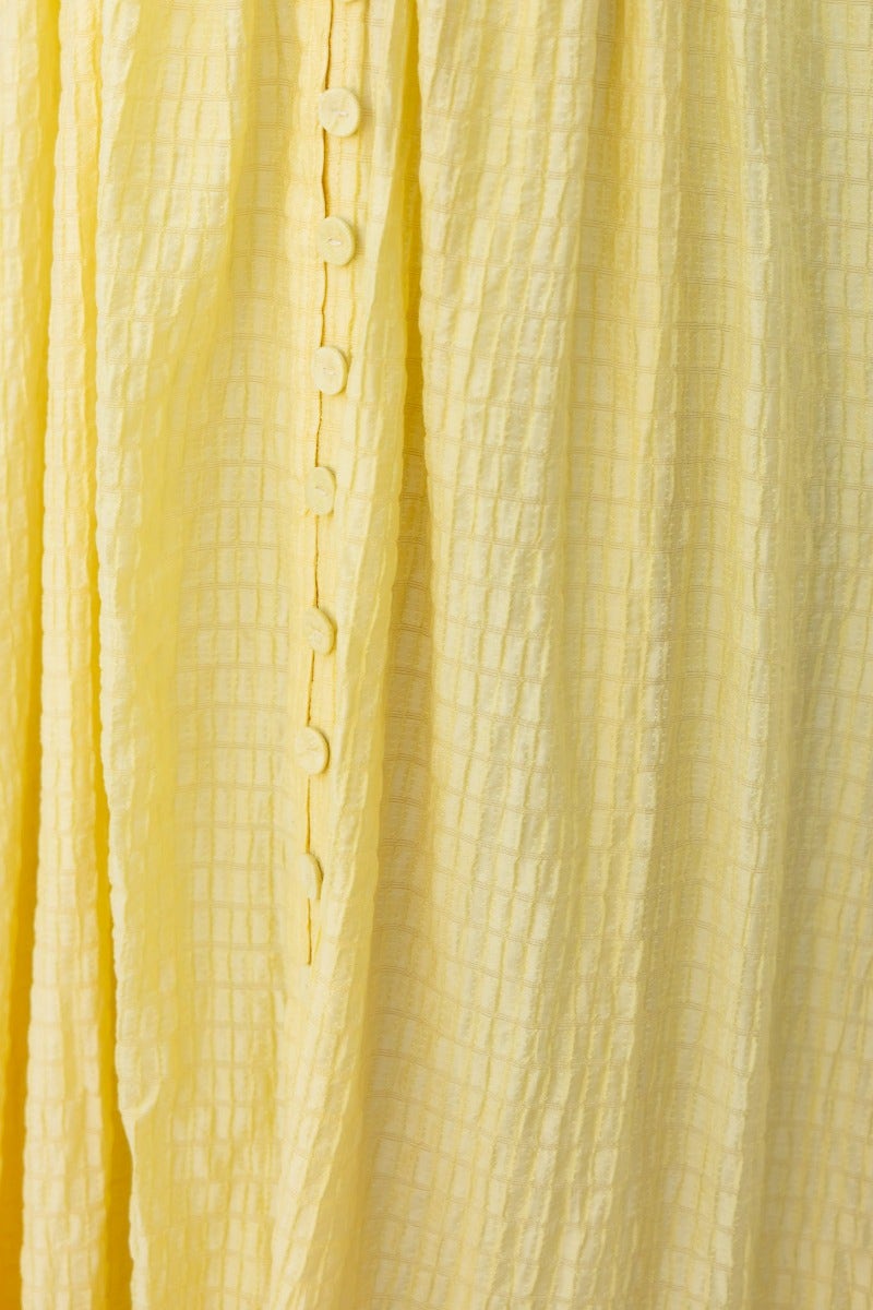 Close-up of textured yellow fabric with faux buttons, highlighting the detail of the Hollie Maxi Dress.