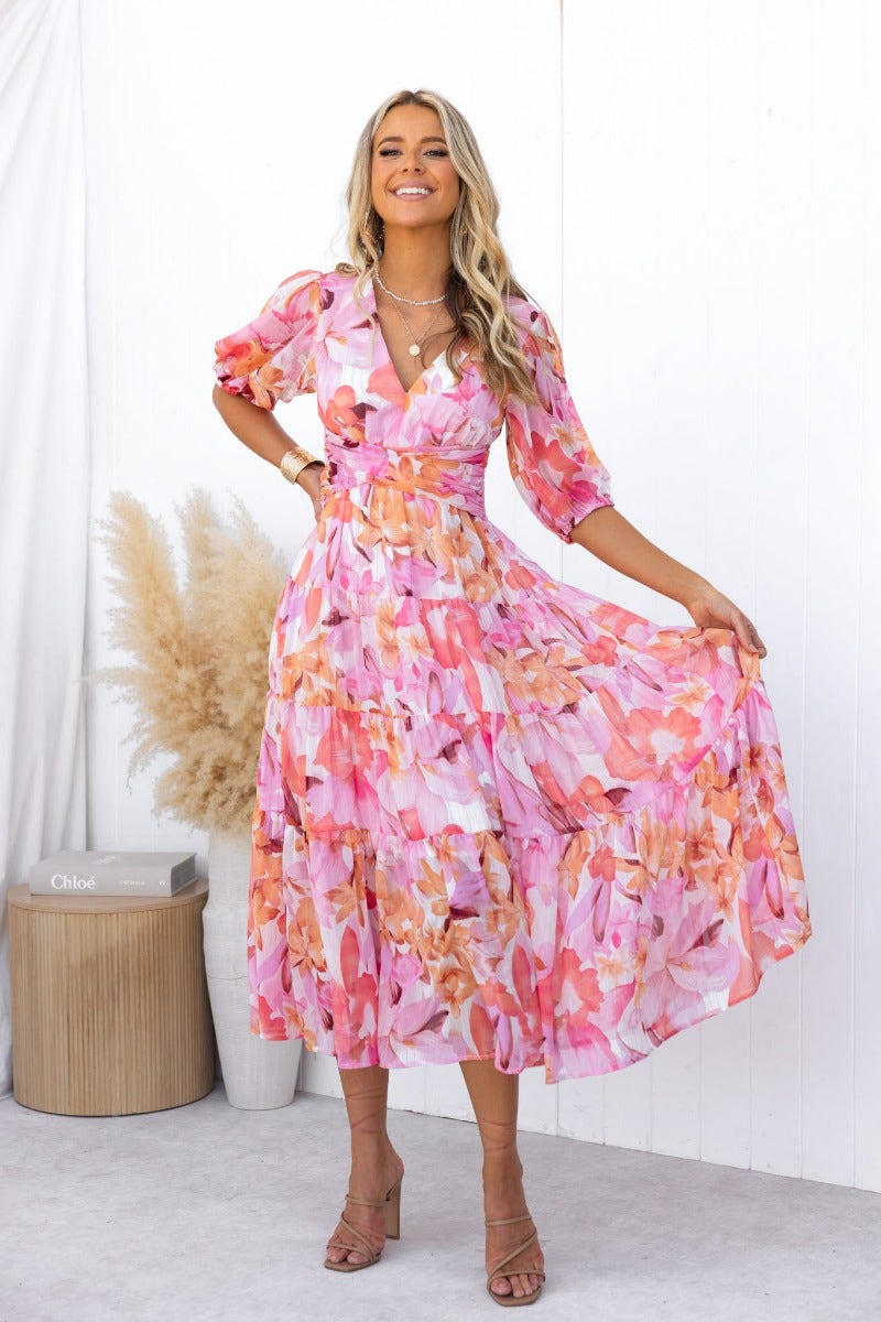Floral print Orchi midi dress with V-neckline and elastic sleeves, styled by a model in a bright setting.