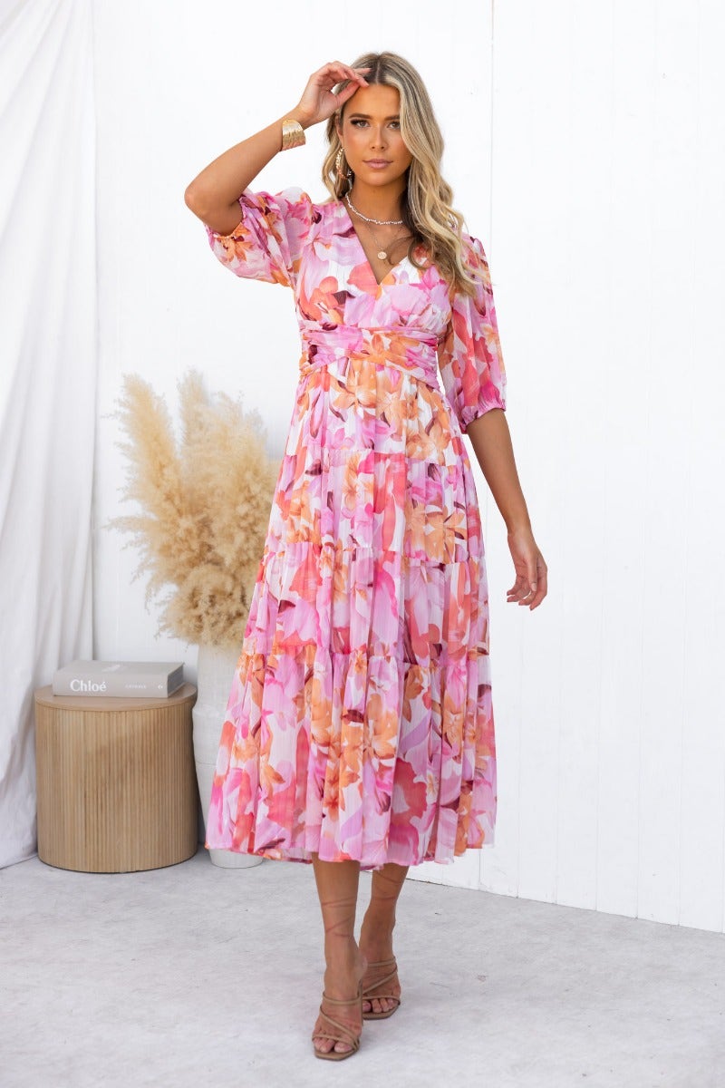 Model wearing the Orchi Midi Dress, a floral print V-neckline dress with elastic sleeves and a flowing skirt.