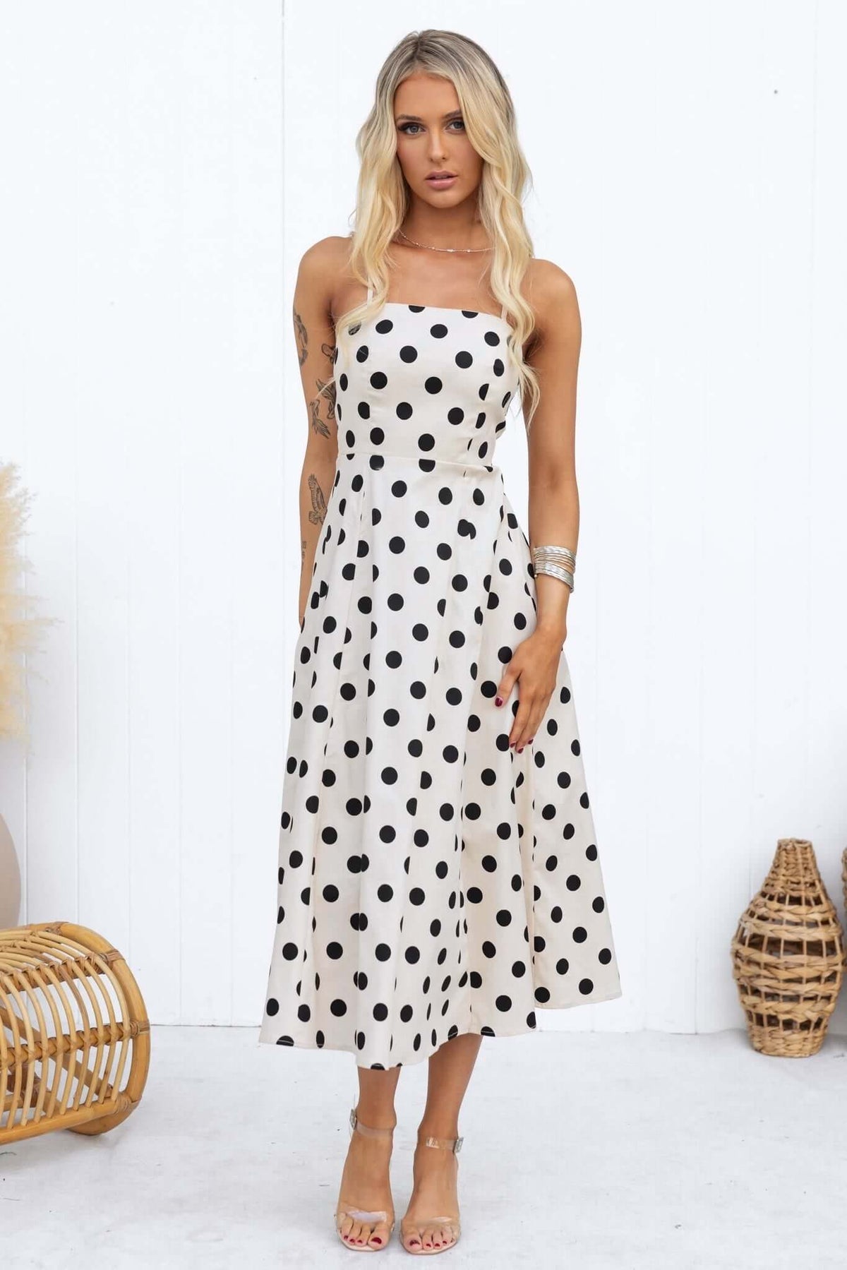Woman wearing a polka dot midi dress with adjustable straps, featuring a square neckline and elegant silhouette.