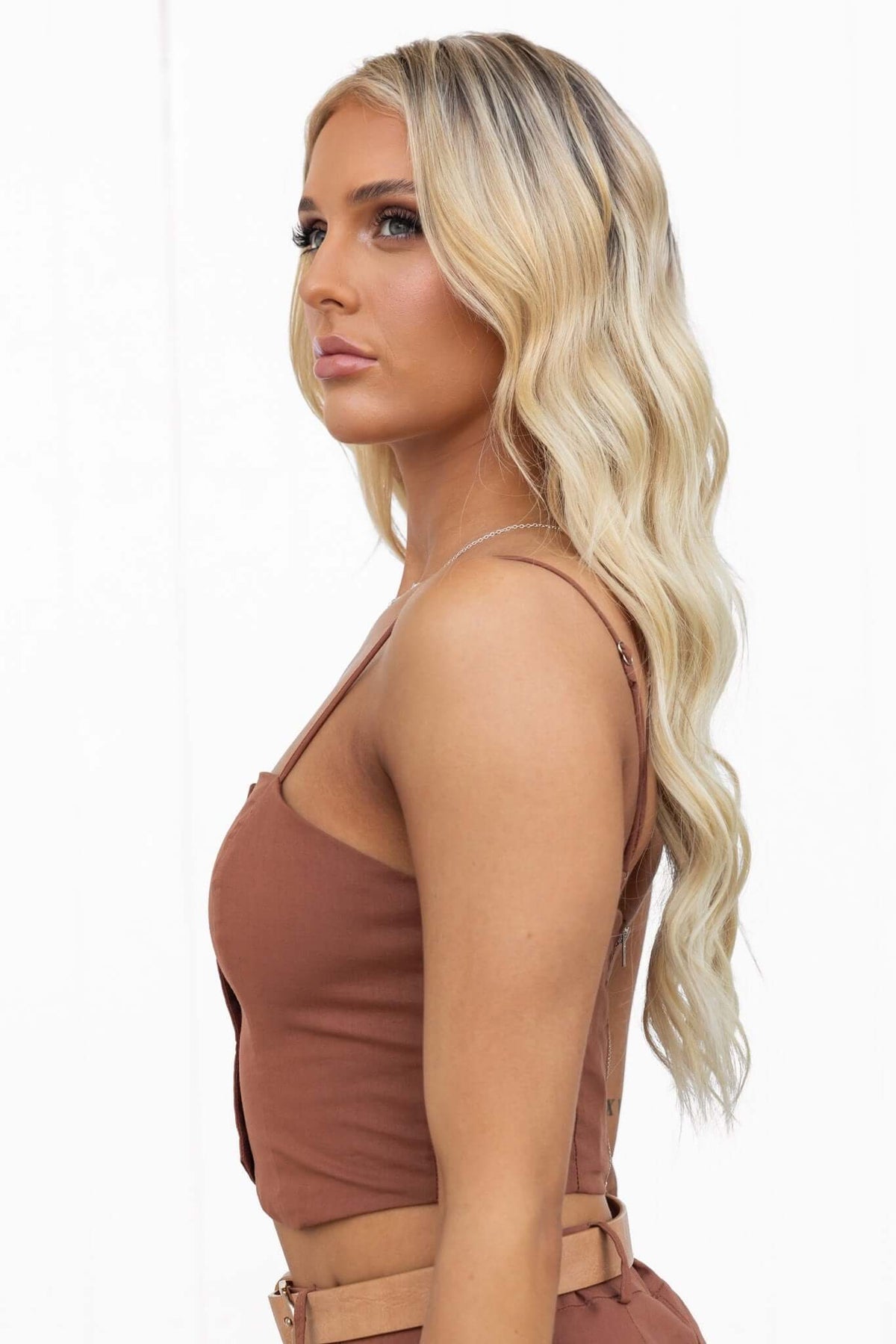 Woman wearing a Downtown Top with adjustable spaghetti straps and fixed button front, styled with wavy hair.