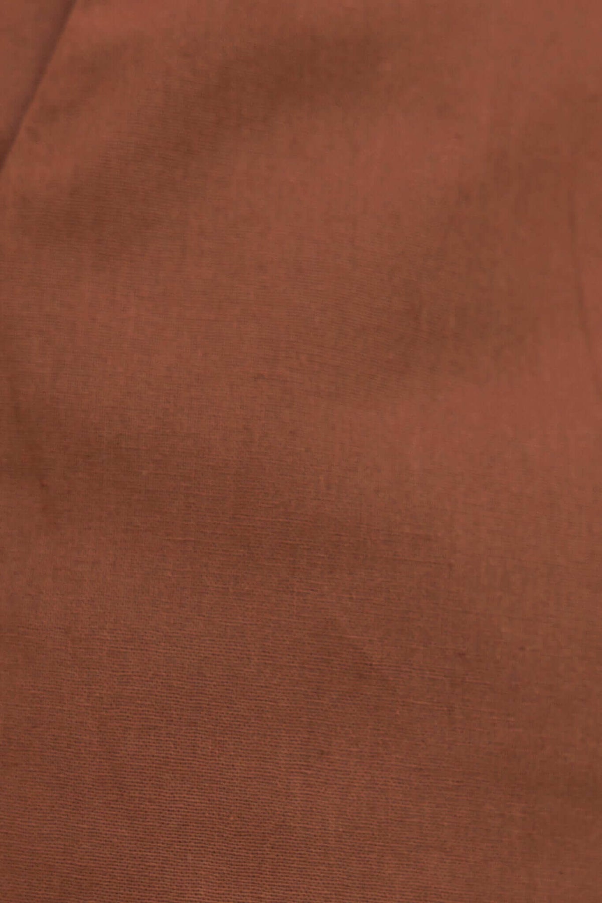 Close-up of smooth, rust-colored fabric texture, showcasing the non-stretch material of the Downtown Top.