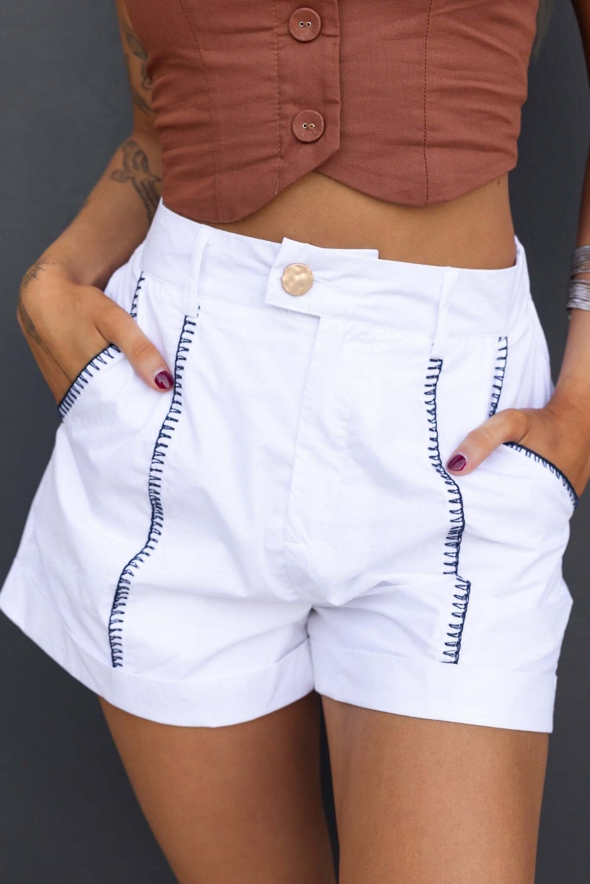 Model wearing Kelso Shorts, mid-high waist white shorts with pockets and contrasting stitching.