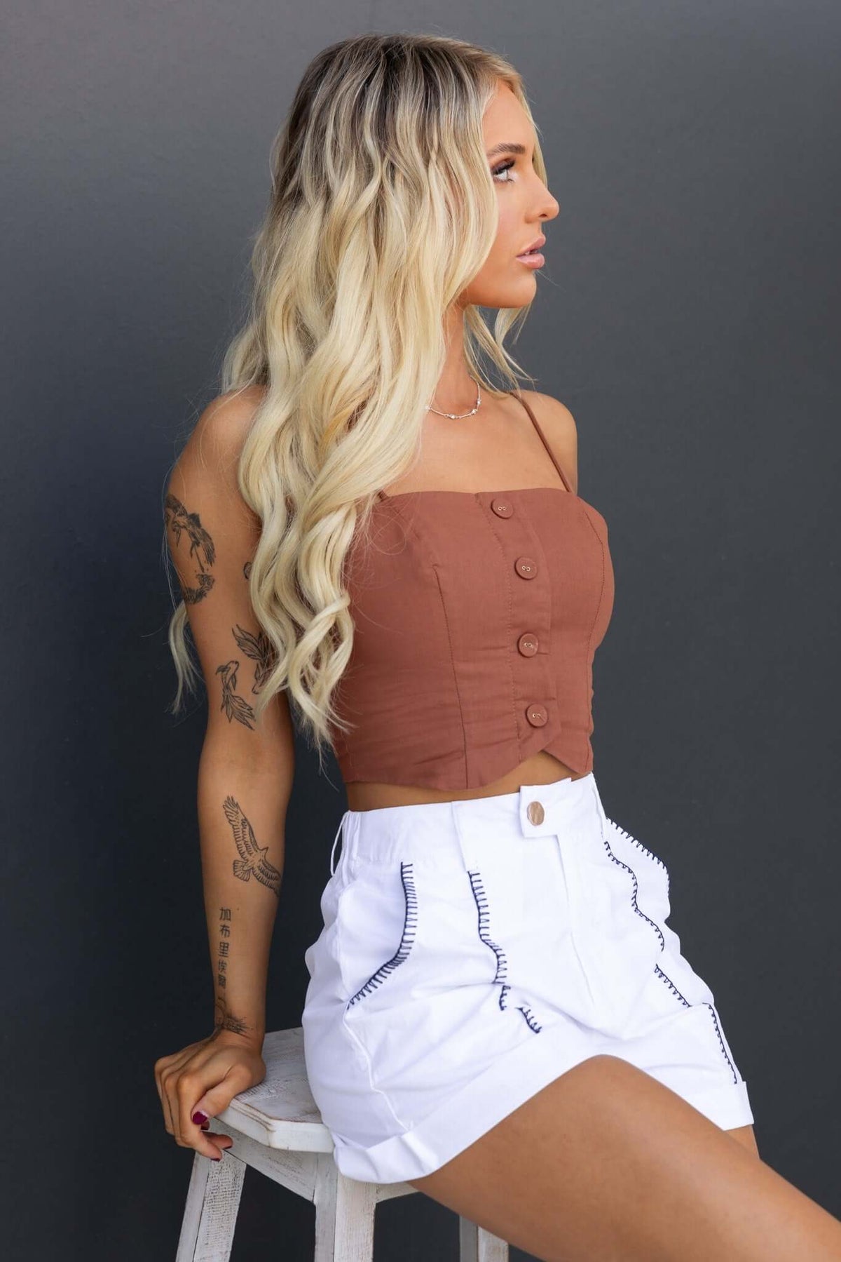 Model wearing Kelso Shorts with a mid-high waist, elastic waistband, and pockets, styled with a brown cropped top.