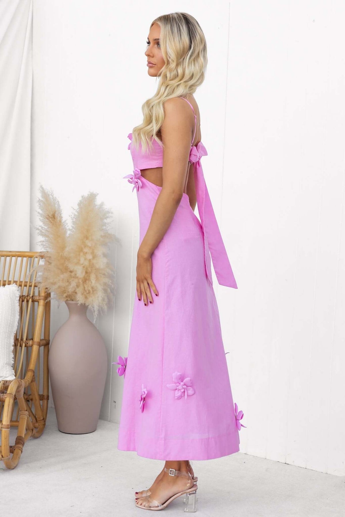 Stylish woman showcasing a pink flower pop midi dress with adjustable straps and cut out sides.