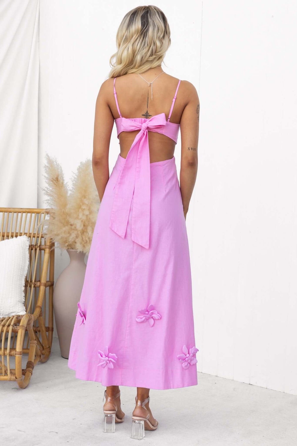 Back view of a Flower Pop Midi Dress featuring a bow tie detail and floral embellishments in pink, perfect for summer occasions.