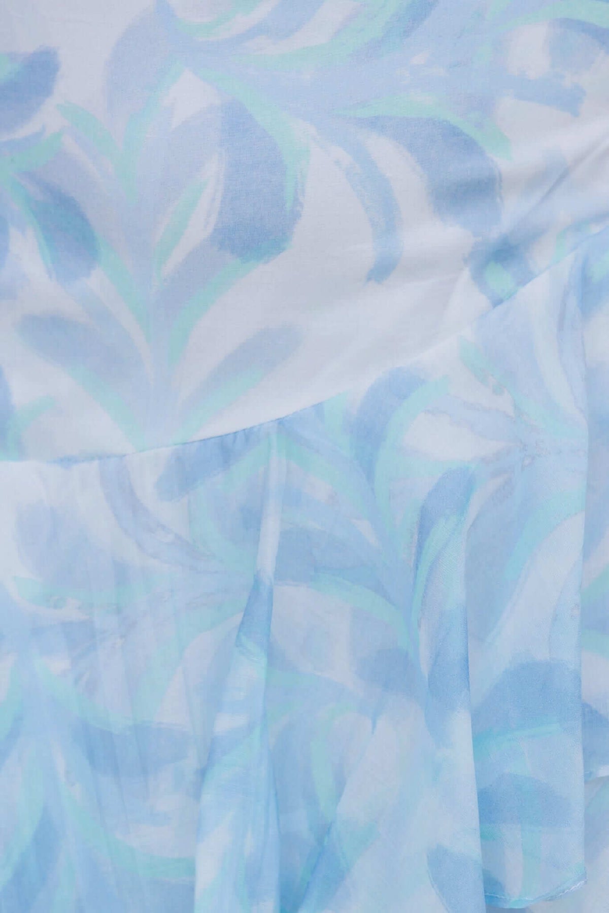 Close-up of the floral print fabric in light blue tones of the Saphina Maxi Skirt, highlighting its chiffon material and ruffle detail.