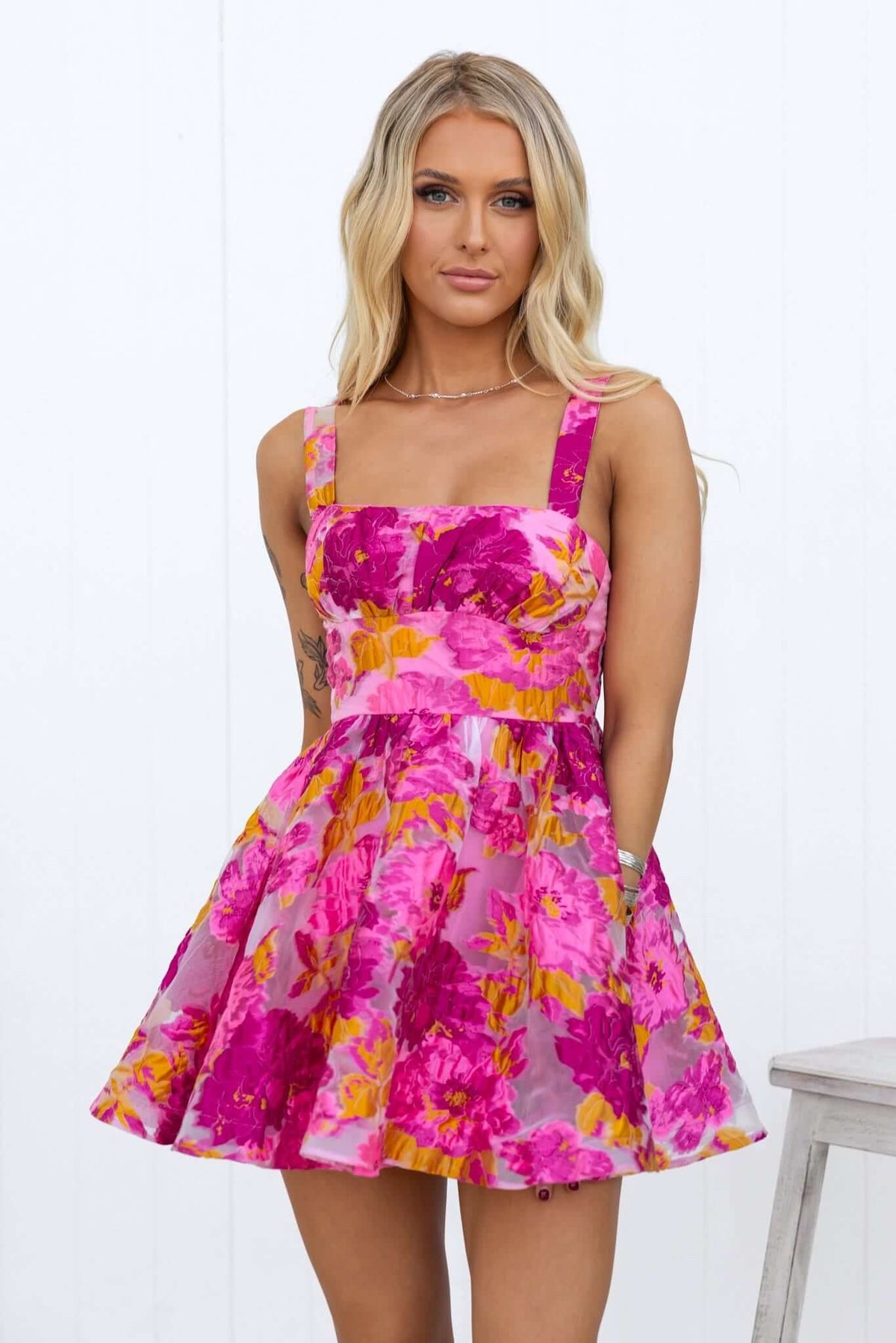 Wander More Dress with adjustable straps and floral pattern in pink and yellow, showcased by model.
