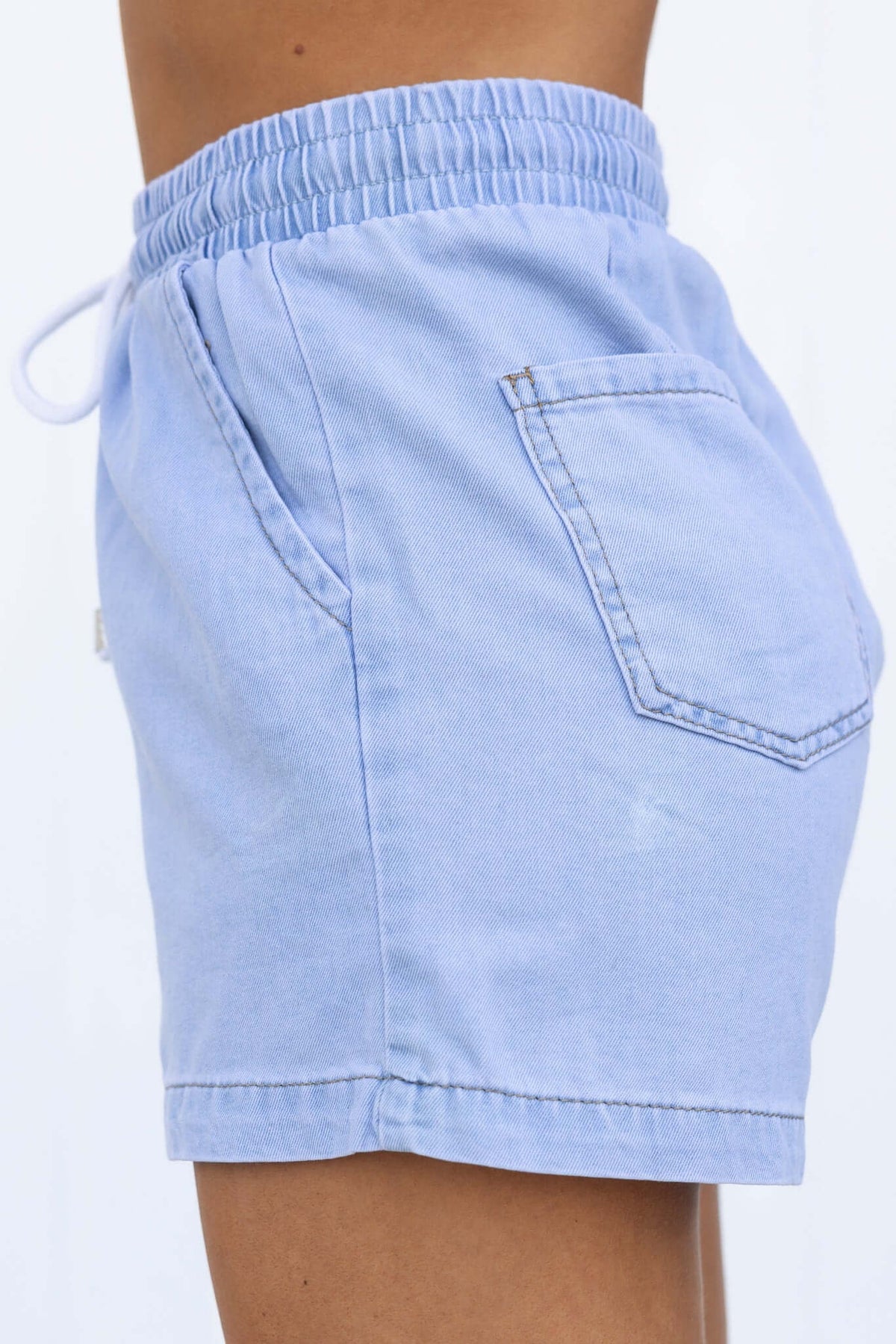 Side view of Winslow Shorts featuring elastic waistband, drawstring tie, and chambray fabric with pockets.