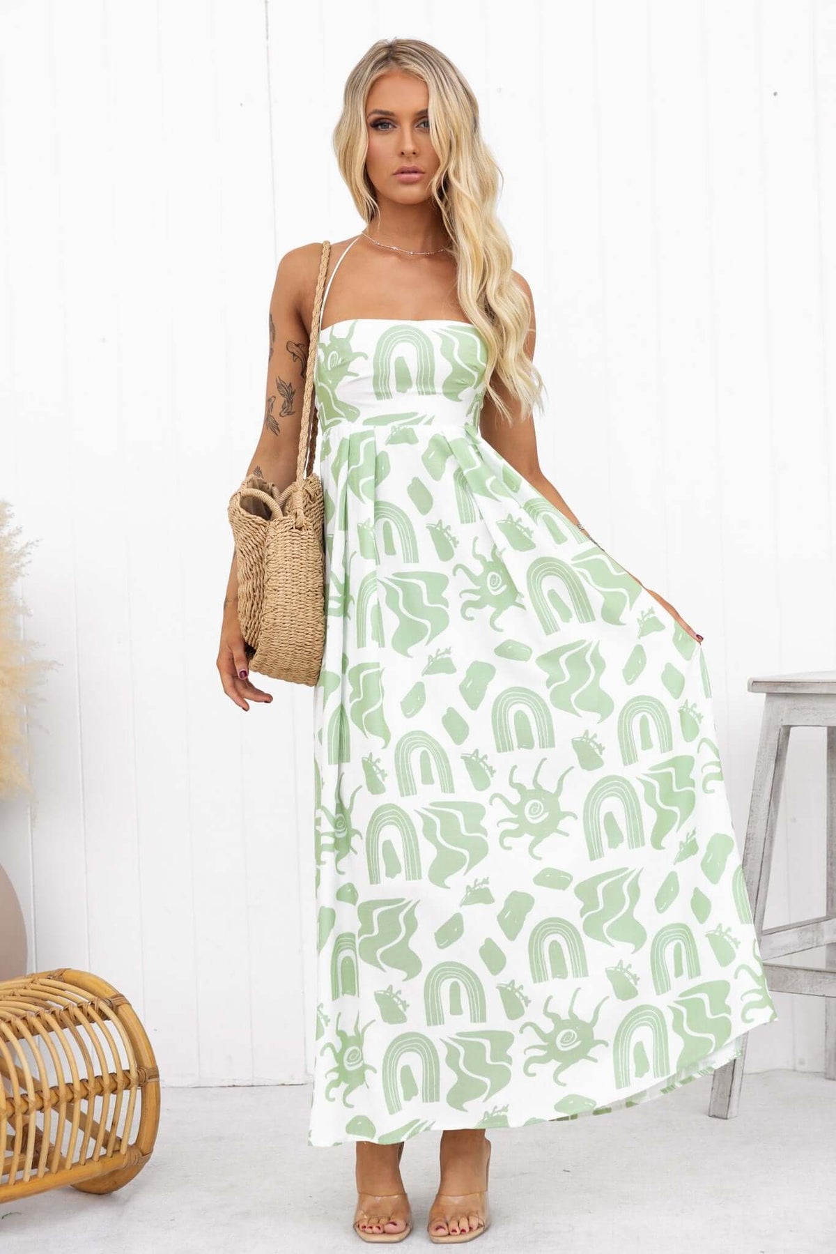 Derry Maxi Dress with adjustable tie straps, square neckline, and green rainbow print, styled with a straw bag.