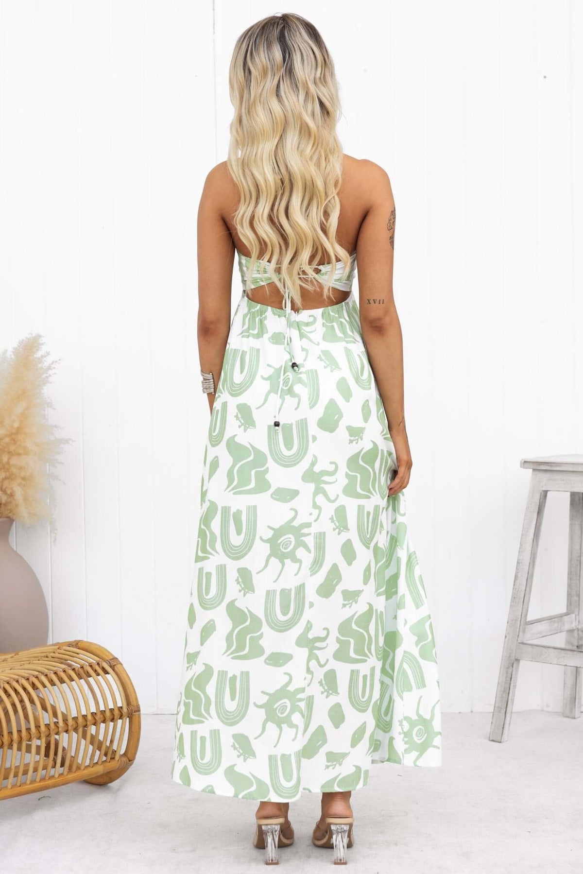Back view of a woman in a Derry Maxi Dress with adjustable tie straps, showcasing a green and white patterned design.