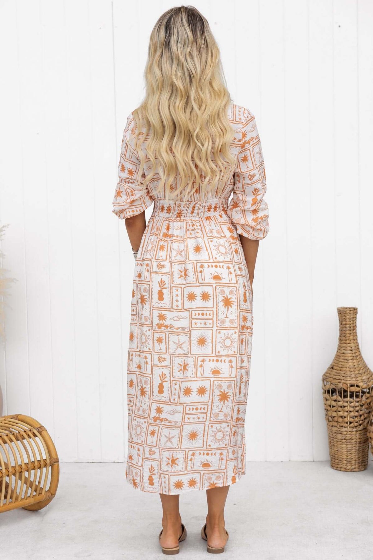 Back view of Brekke Midi Dress featuring a V-neckline, button-up front, and elastic sleeves with a unique pattern.