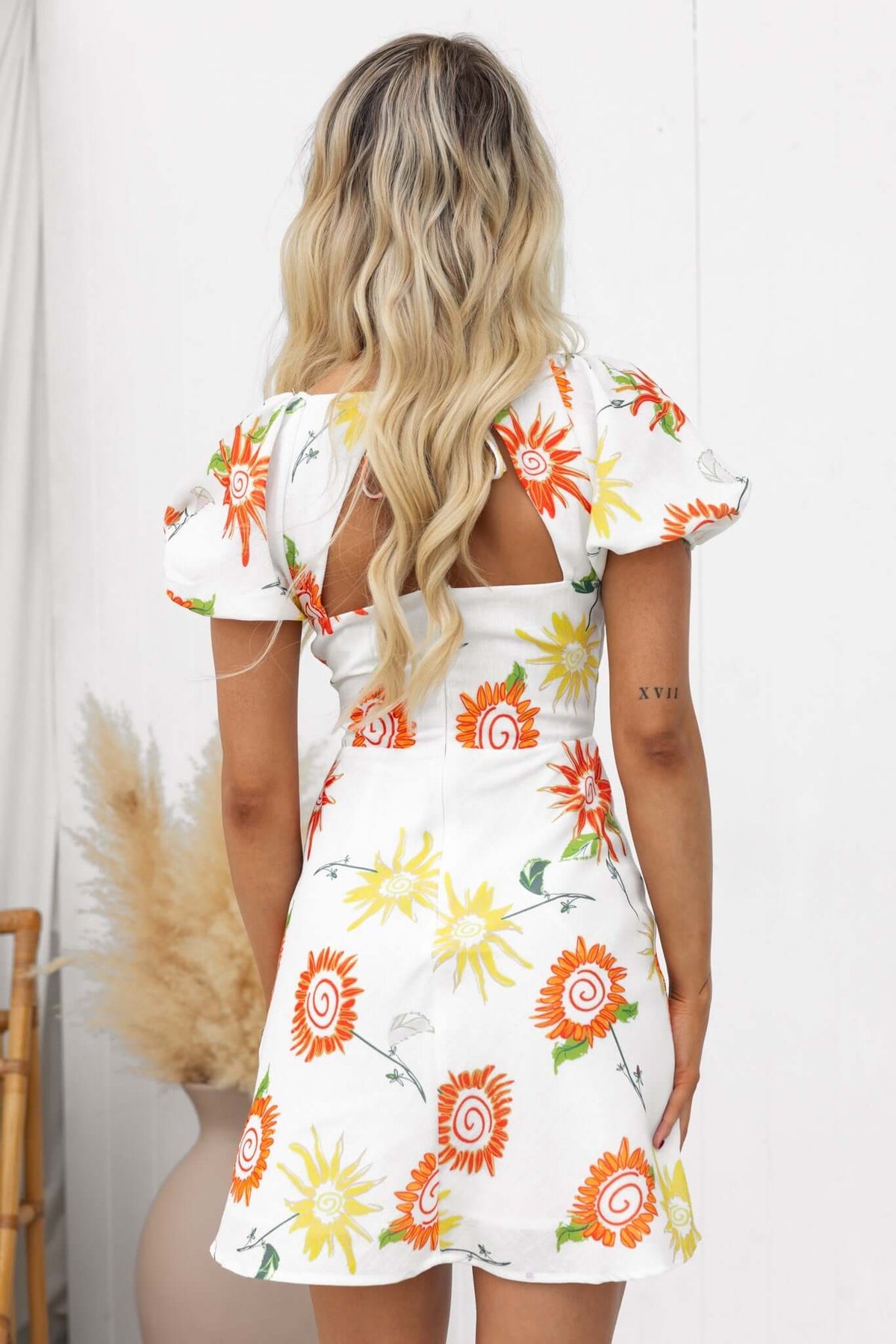 Back view of the Seeker Dress featuring a vibrant floral print, V-neckline, and tie detail.