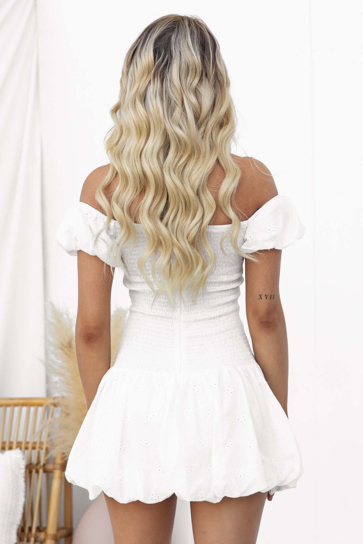 Back view of a woman in a white Fairfield Dress with puff sleeves and a tiered skirt, showcasing the Anglaise material.