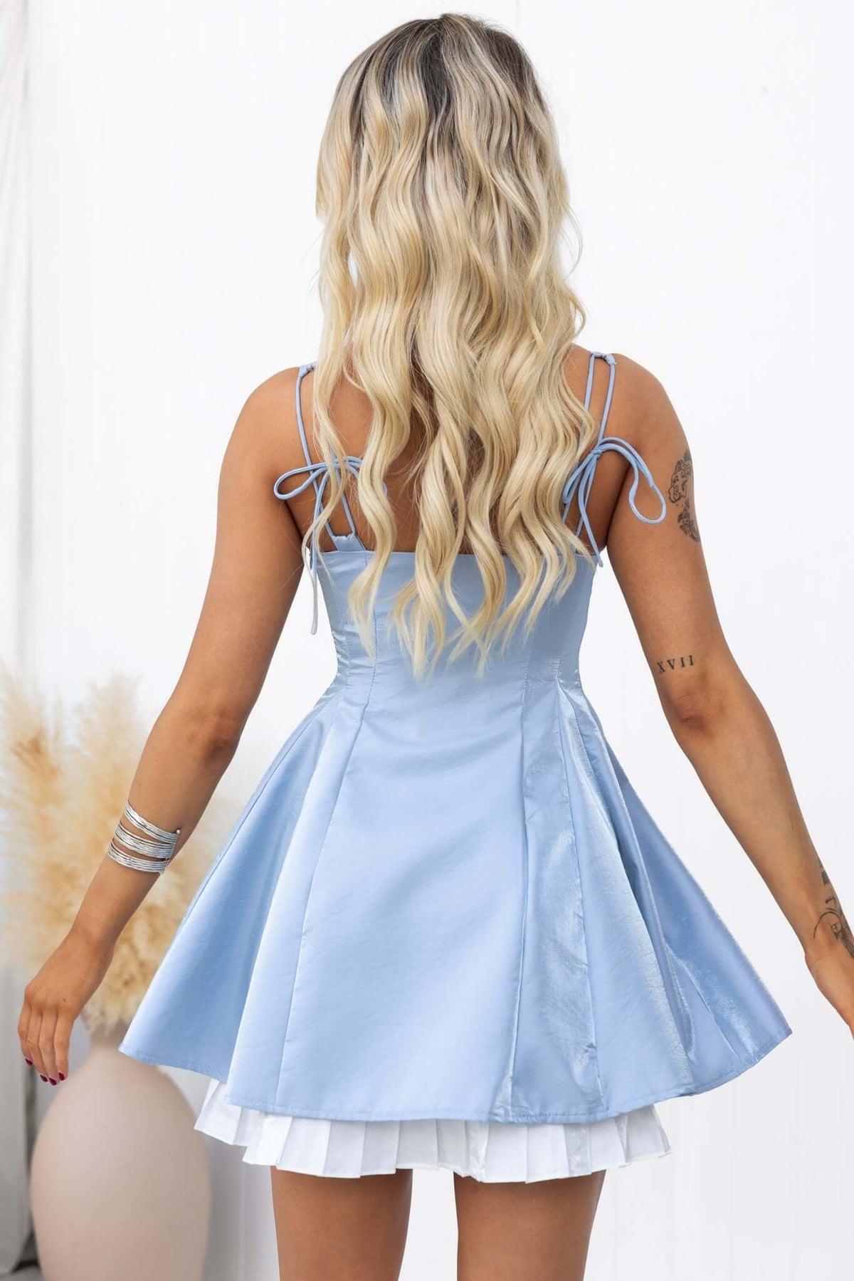 Back view of Yalena Mini Dress in light blue, featuring tie straps and flared skirt.