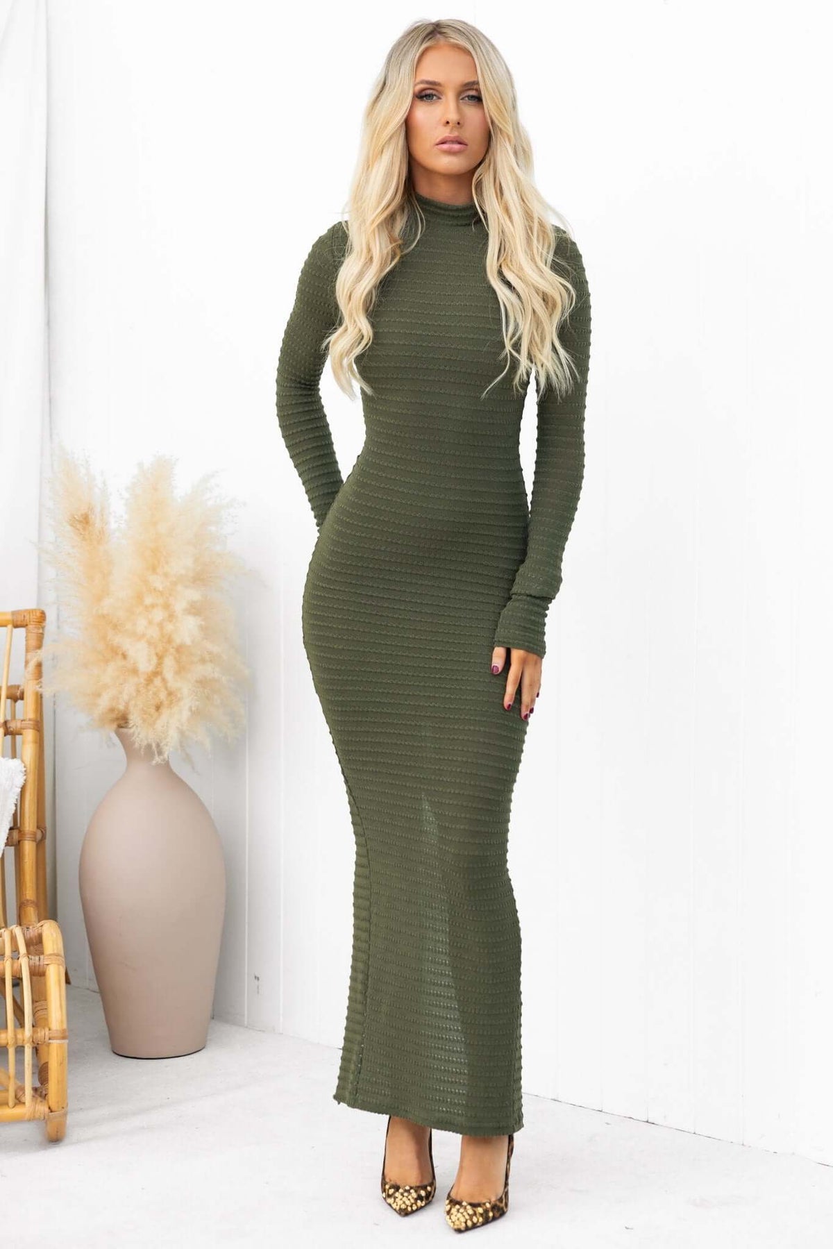 Model wearing Everlie maxi dress in olive green with high neckline and textured material, styled with leopard print heels.