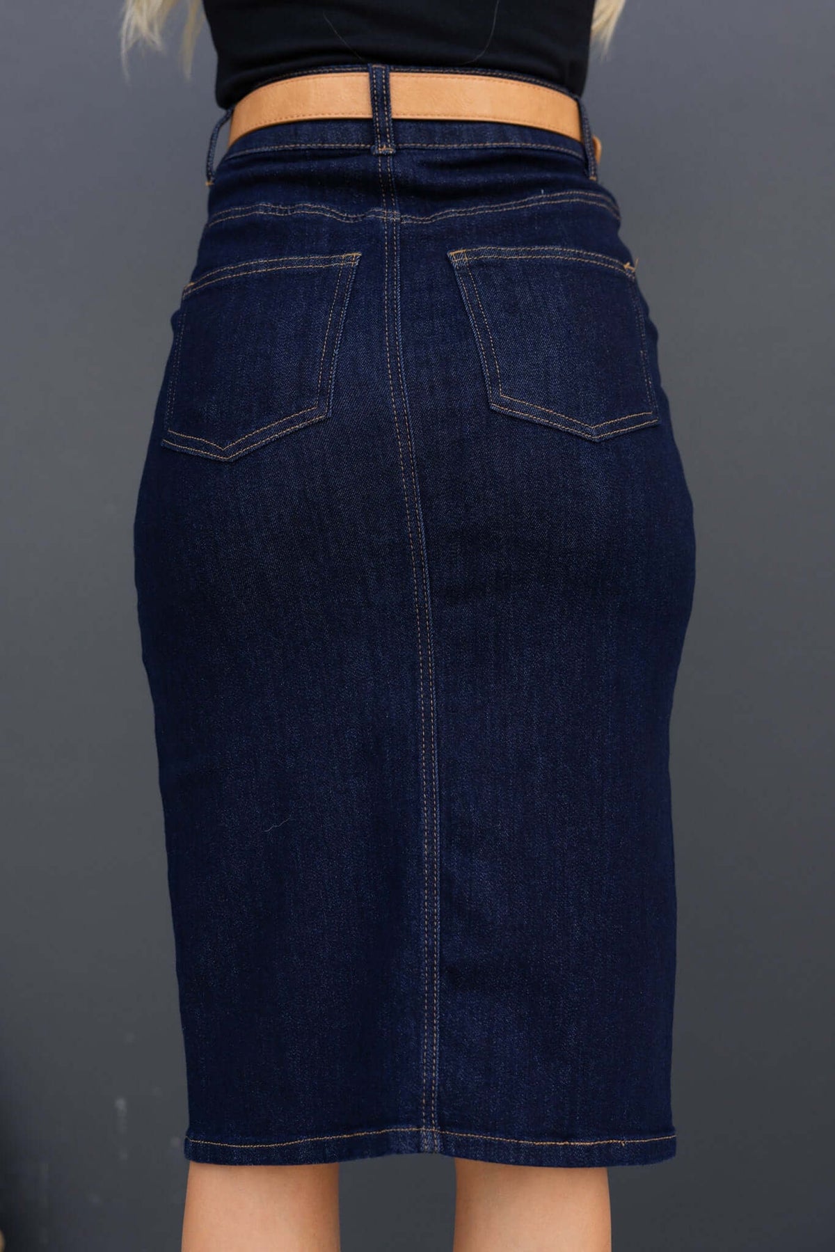 Back view of the Ella Denim Midi Skirt in dark navy, showcasing pockets and a fitted silhouette.