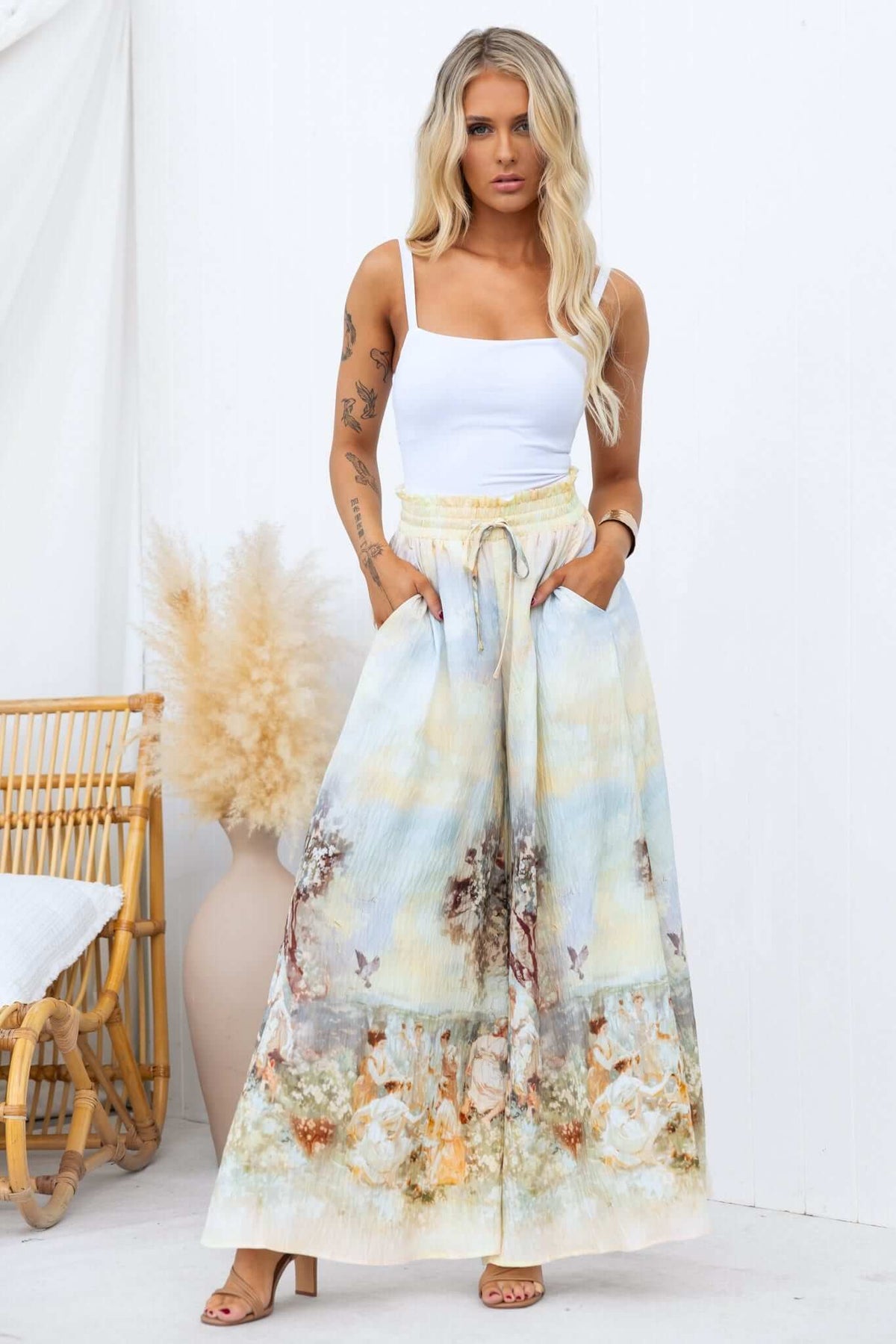 Model wearing Grafton Pants with an abstract floral print, mid-high waist, wide legs, and pockets, styled for a summer look.
