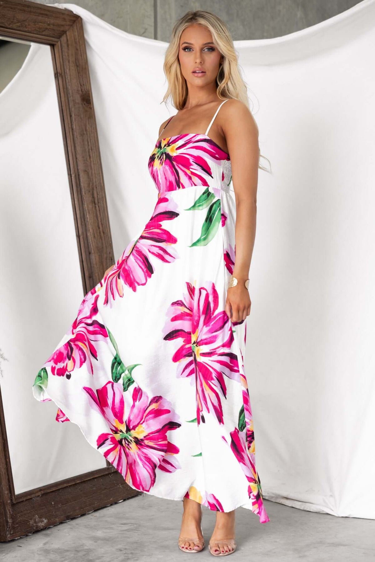 Woman wearing a floral Salilah Maxi Dress with thin straps and pockets, standing against a mirror backdrop.