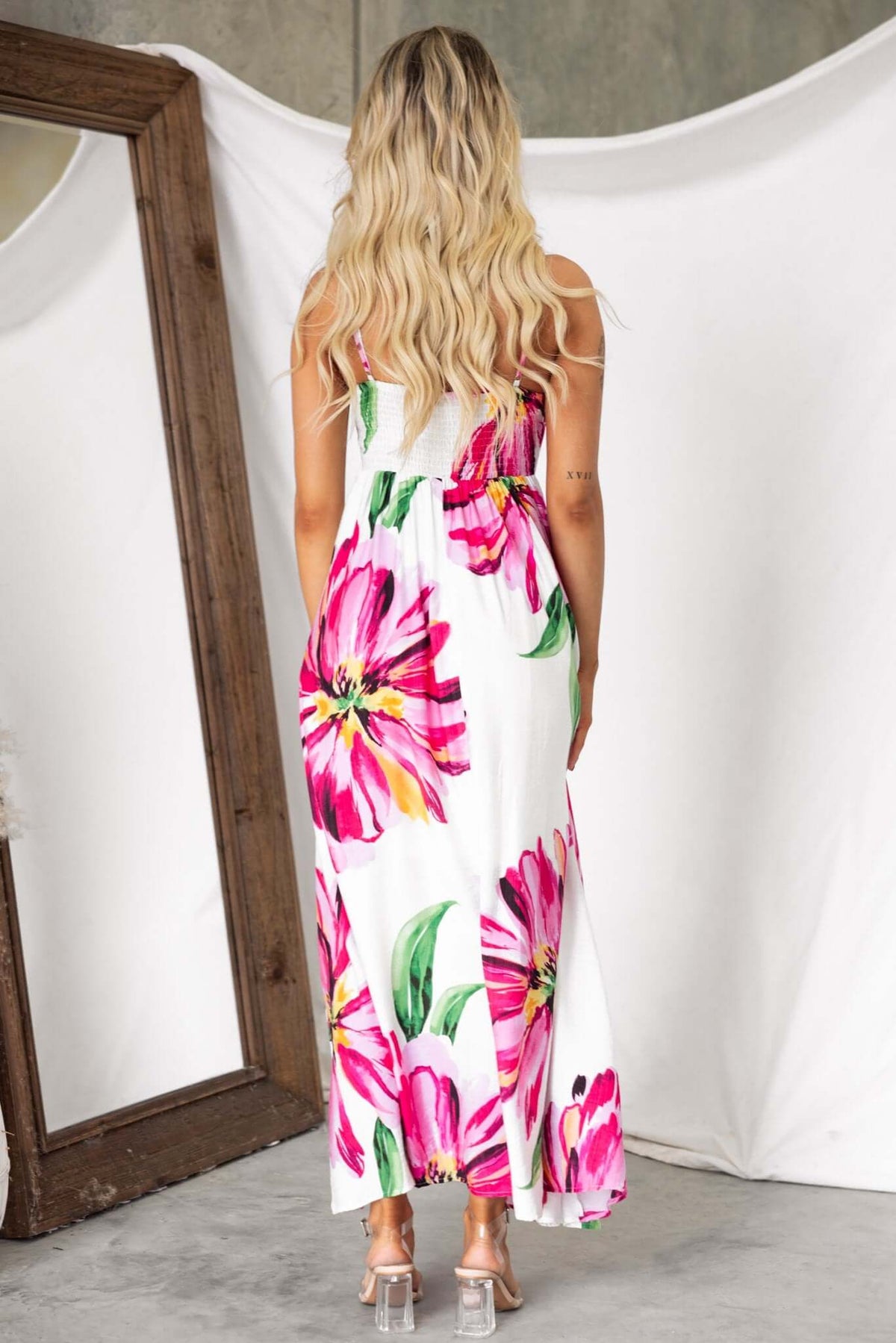 Back view of a woman in a vibrant floral Salilah Maxi Dress with thin straps and a shirred panel.