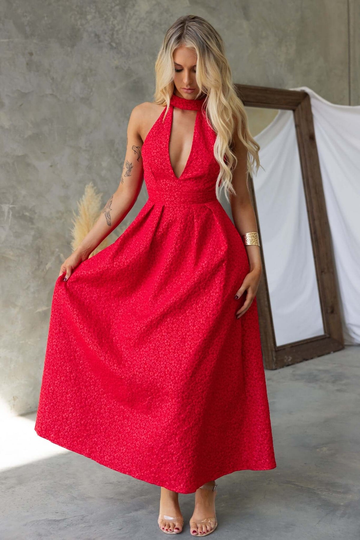 Elegant red Ultima Maxi Dress with textured detail, pleated waist, and halter neck design. Perfect for special occasions.