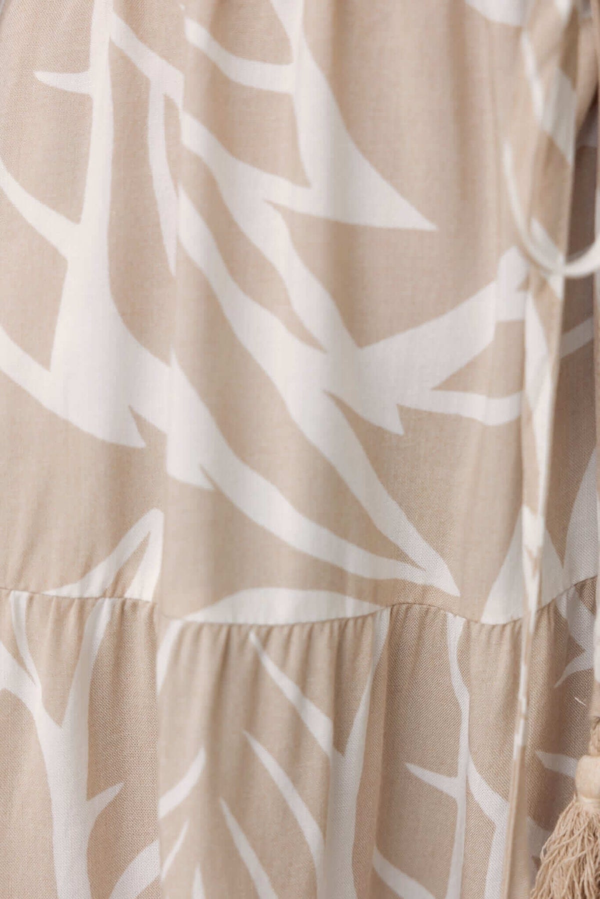 Close-up of the Danza Dress showing a beige and white abstract pattern, featuring a tiered design and soft fabric texture.