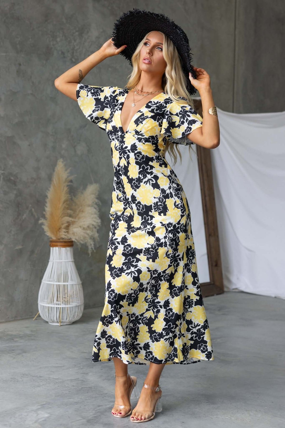 Model wearing a black and yellow floral Bartow Maxi Dress with V-neckline and flowing sleeves.