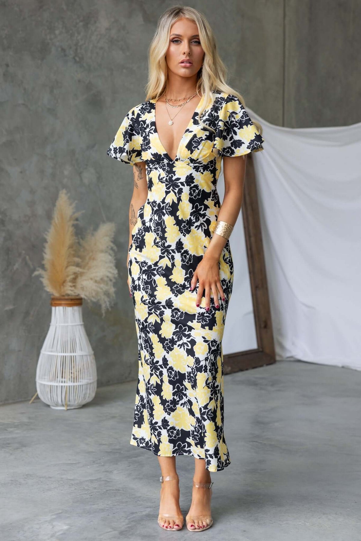 Model wearing the Bartow Maxi Dress featuring a black and yellow floral design and a flattering V-neckline.