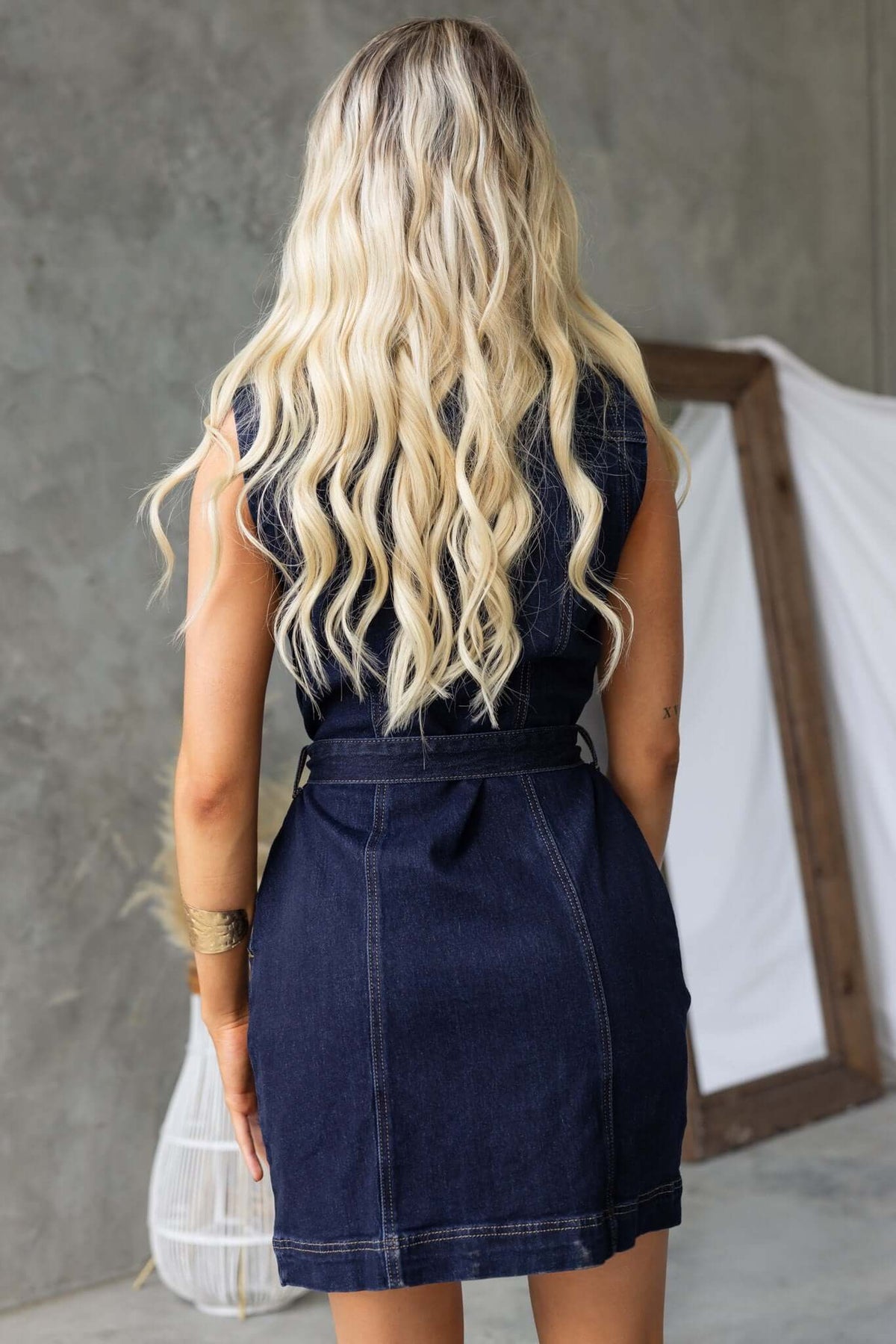 Back view of a woman in a Pokey Denim Dress with a belt, showcasing a stylish and casual look.