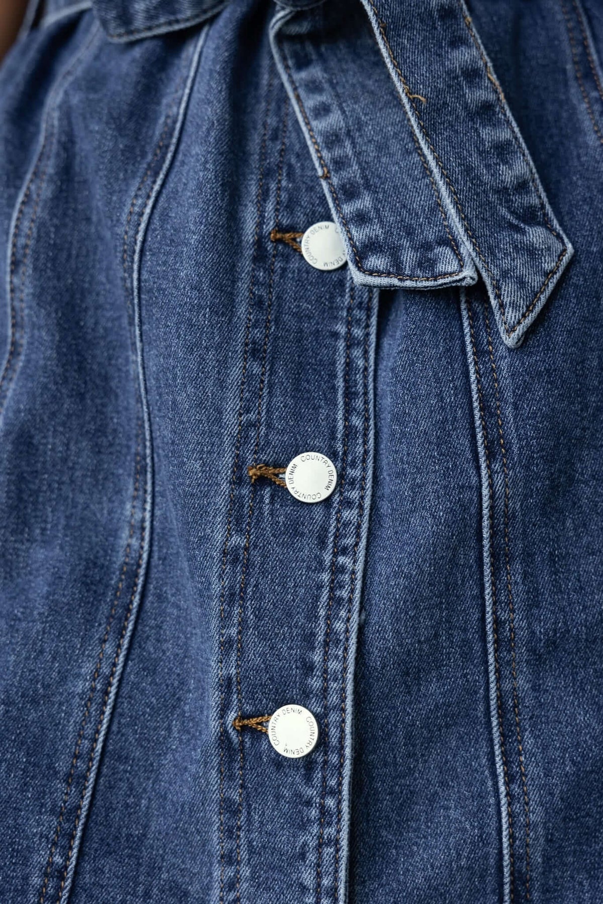 Close-up of Pokey Denim Dress featuring button-up front, collar, and removable belt in blue denim.