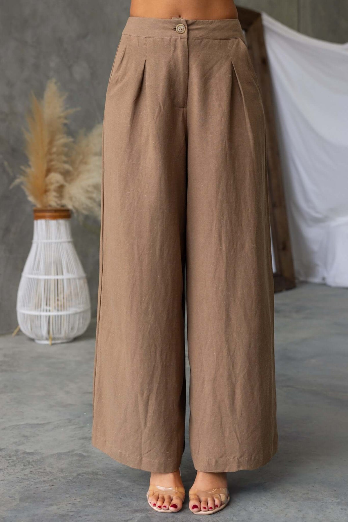 Brown wide-leg pants featuring a mid-high waist, pockets, and a linen look, perfect for summer wear.
