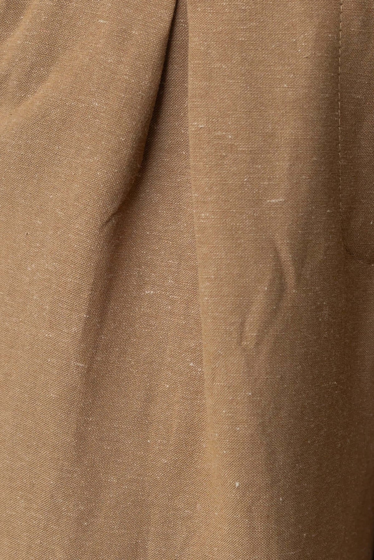 Close-up of Carters pants fabric in a warm brown linen blend, showcasing its textured feel and subtle creases.