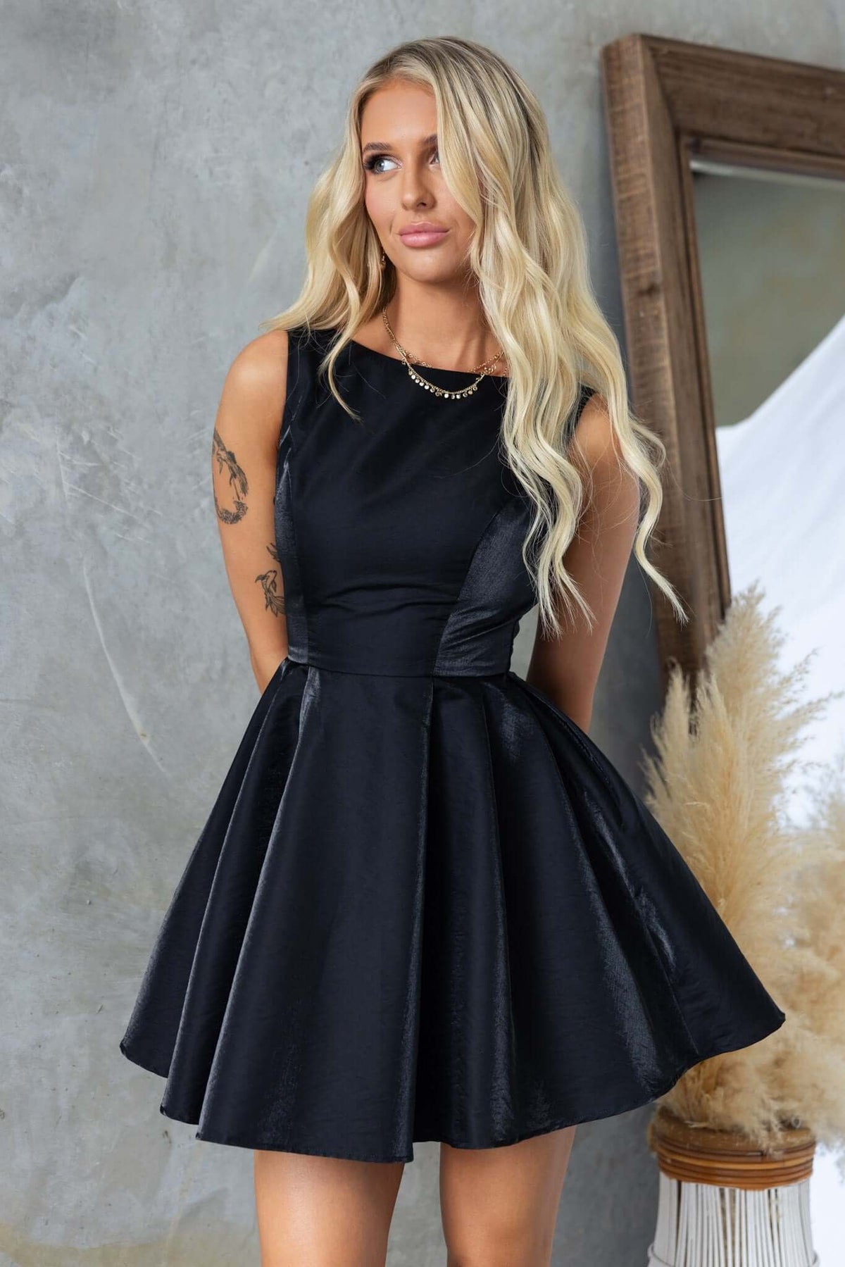 Sandy Dress featuring a high neckline and satin finish, modeled by a woman with long hair, showing a fitted bodice and flared skirt.