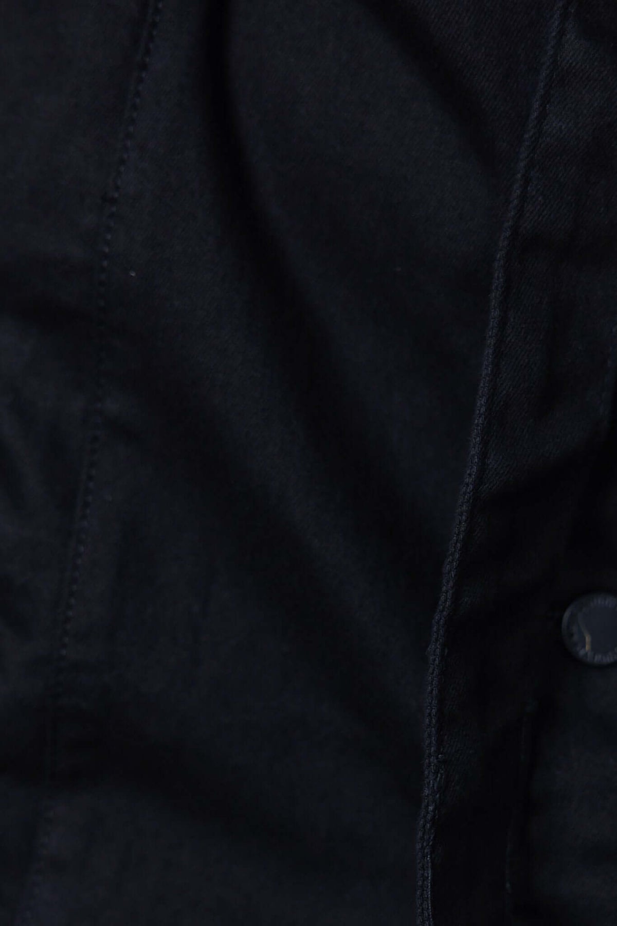 Close-up of black denim fabric featuring stitching and button detail for Forever Me Denim Dress.