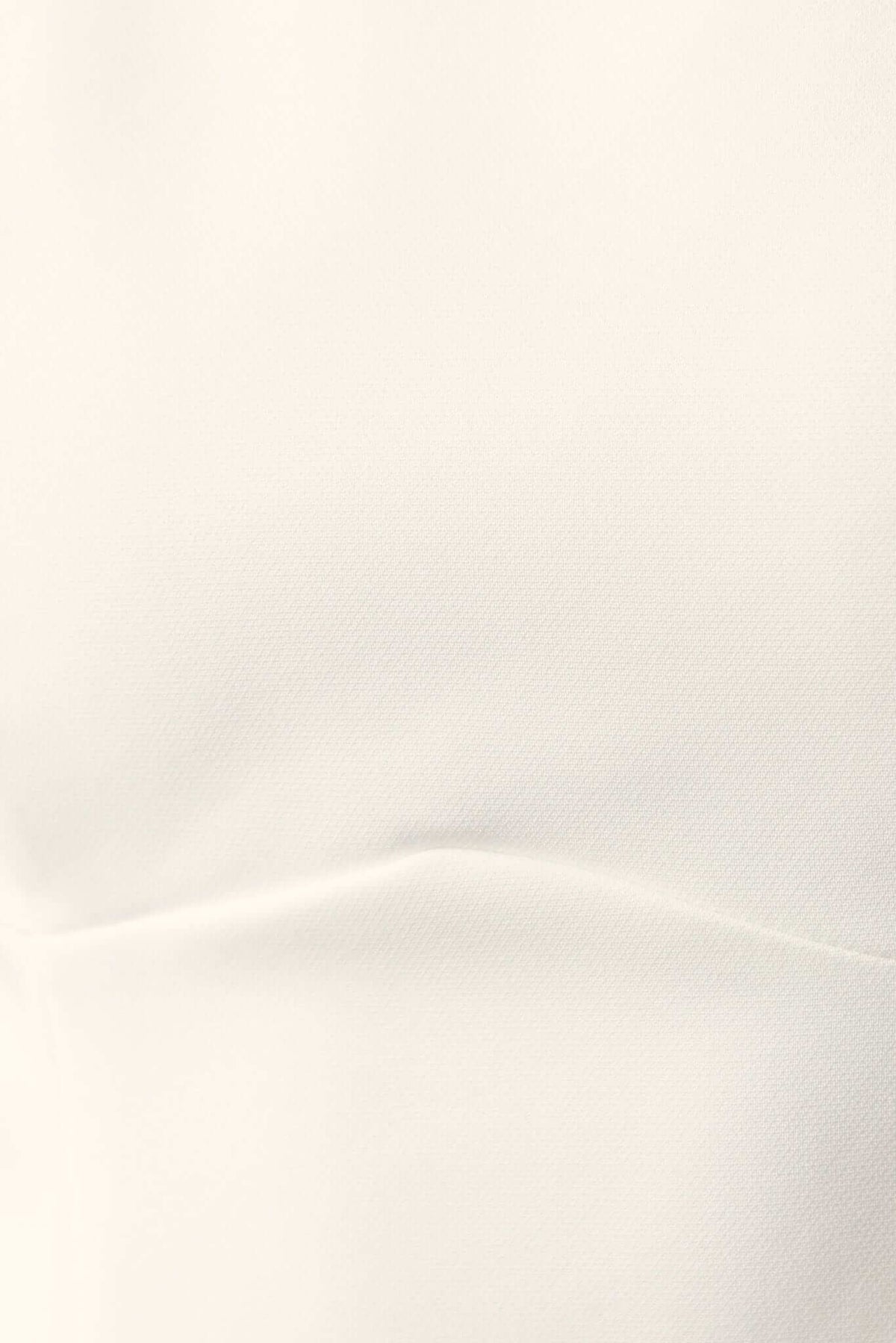 Close-up of the fabric texture of the Demure Dress in a soft white tone. Smooth, non-stretch material with subtle details.