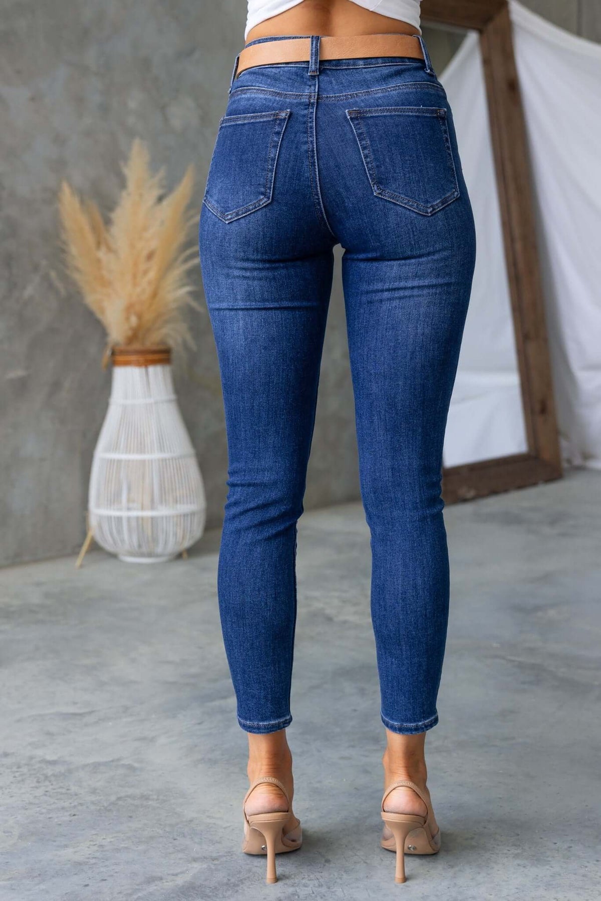 Skinny fit denim jeans with a mid-high waist and pockets, showcased from the back on a model in a stylish setting.