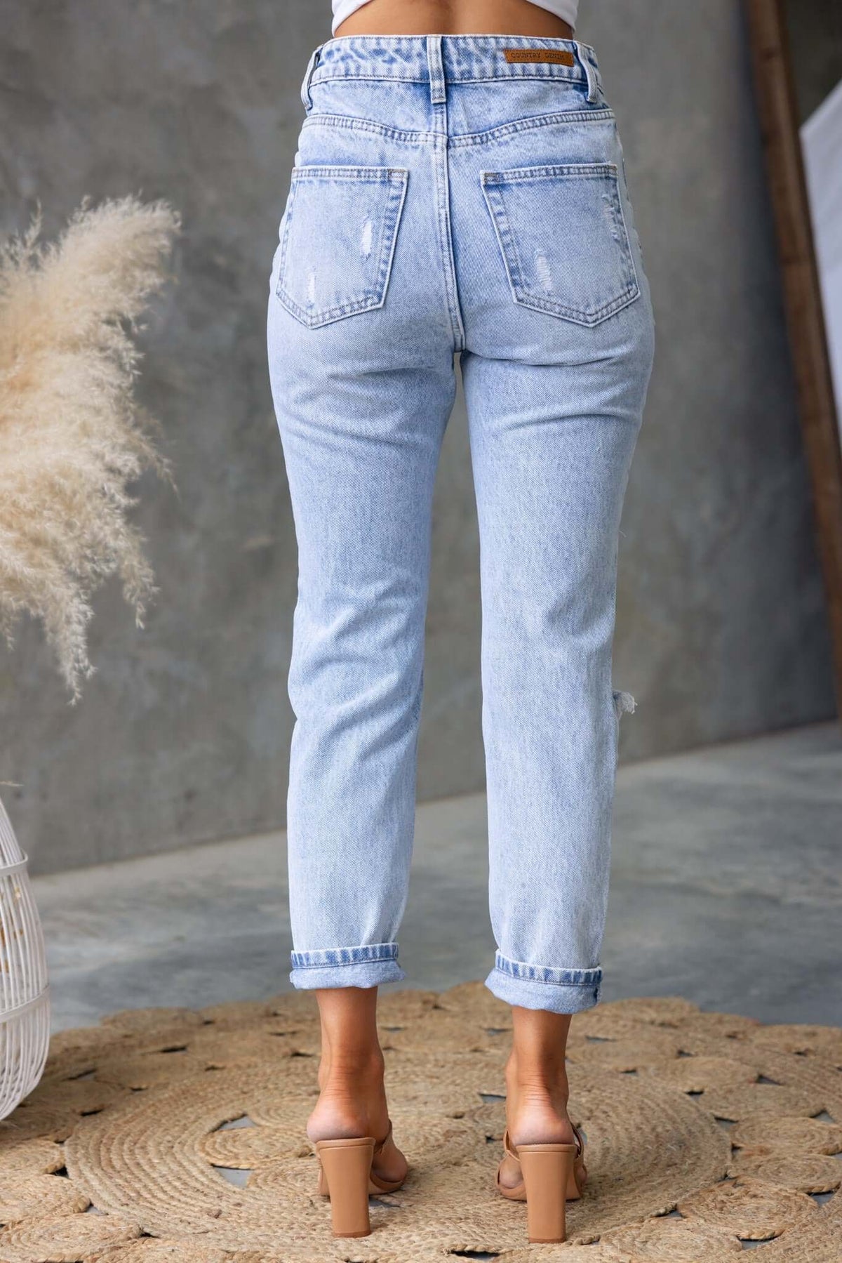 Back view of Niles Jeans in light blue denim with mid-high waist, distressed details and rolled cuffs.