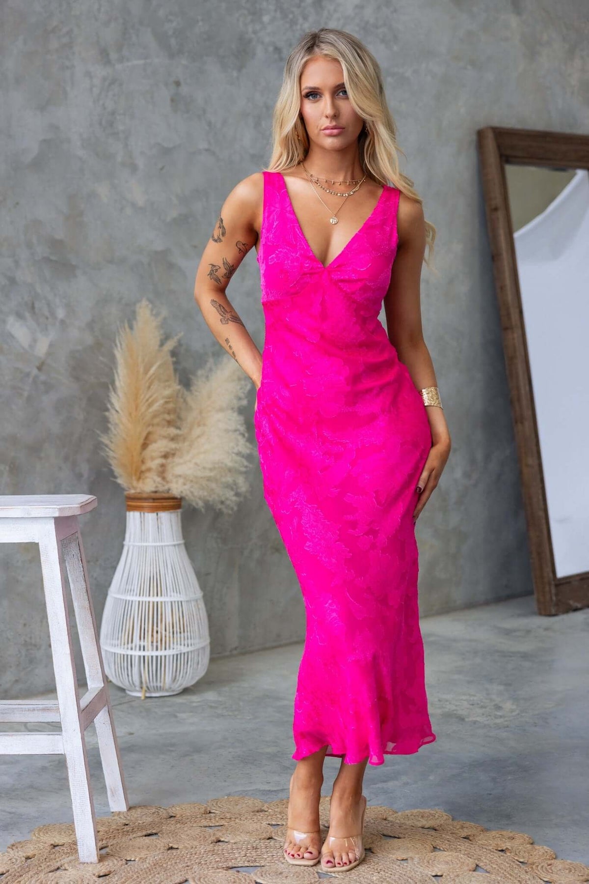 Model wearing vibrant pink Qilax Maxi Dress with textured flower print, showcasing a fitted silhouette and elegant design.