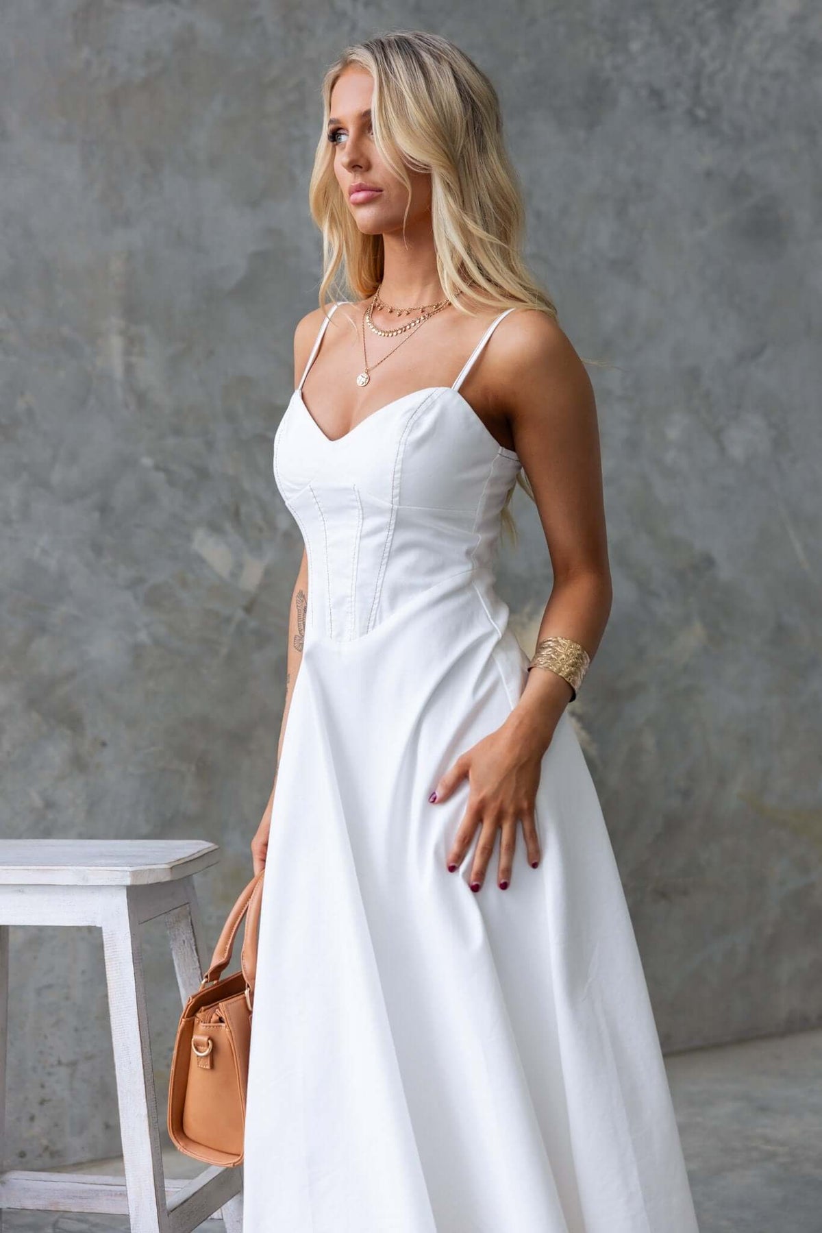 Model wearing a stylish white denim midi dress with adjustable straps and elegant design.