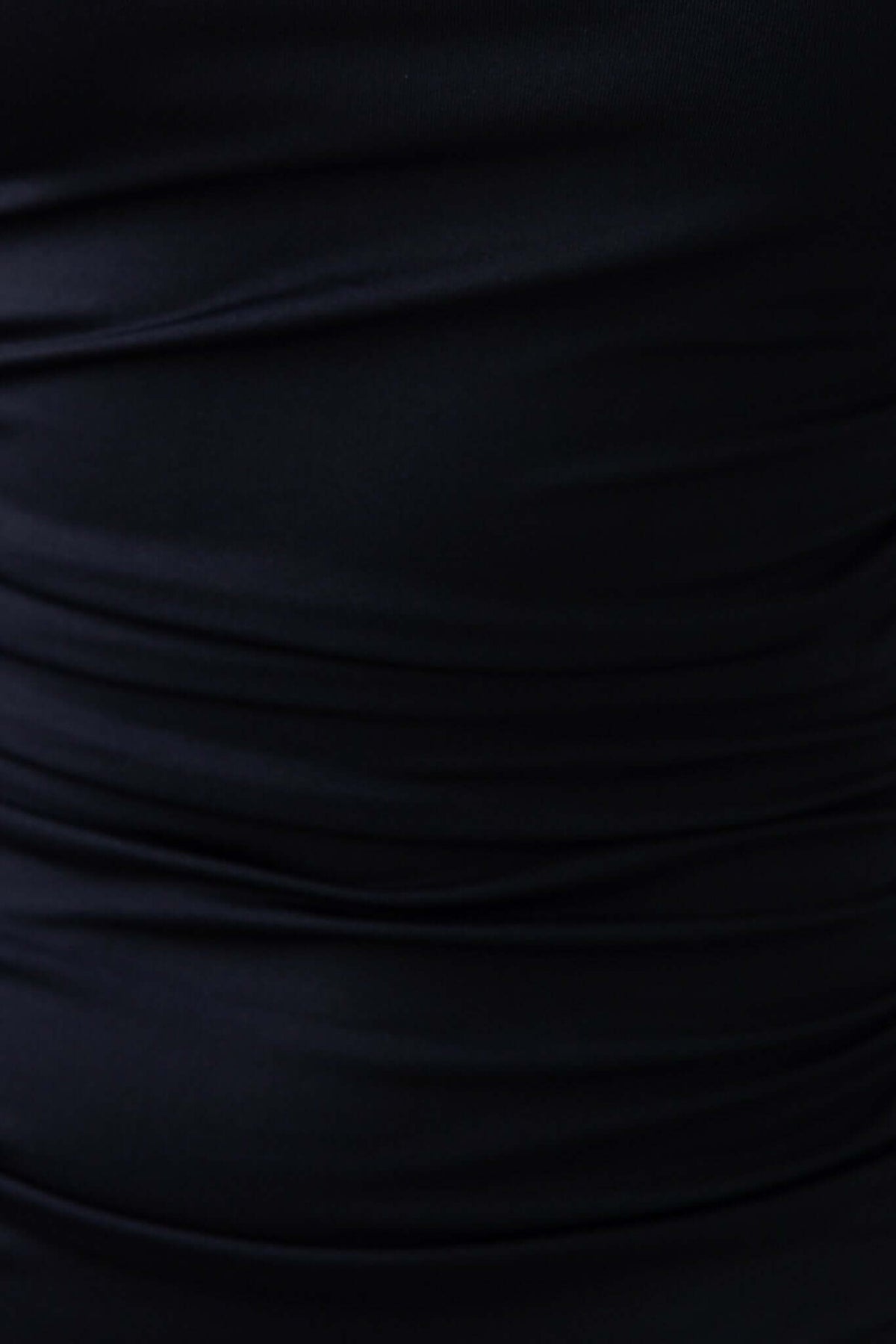 Close-up of smooth black fabric with gathered texture, showcasing the stretchy material of the Martinez Dress.
