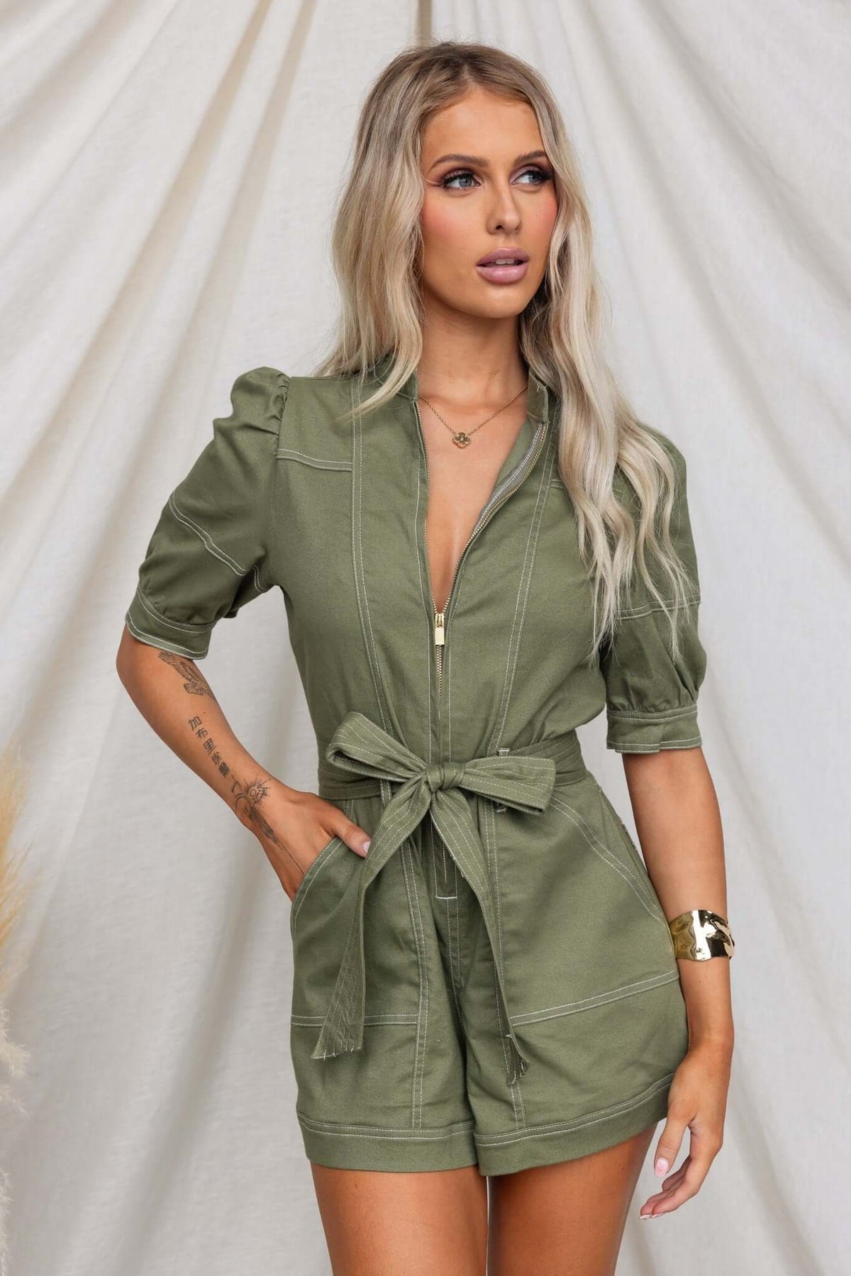 Jade denim playsuit featuring a zip-up front, elastic sleeves, and a removable belt.
