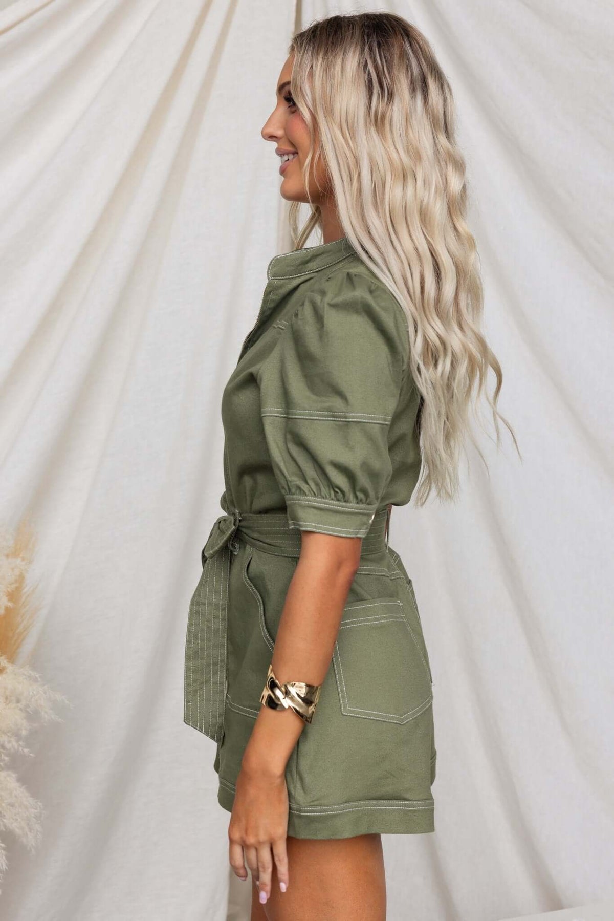 Jade denim playsuit with zip-up front, pockets, and removable belt, showcased from the side.
