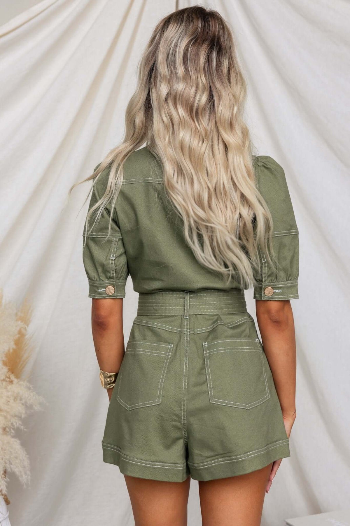 Back view of jade denim playsuit with short sleeves, wide waistband, and pockets on shorts.