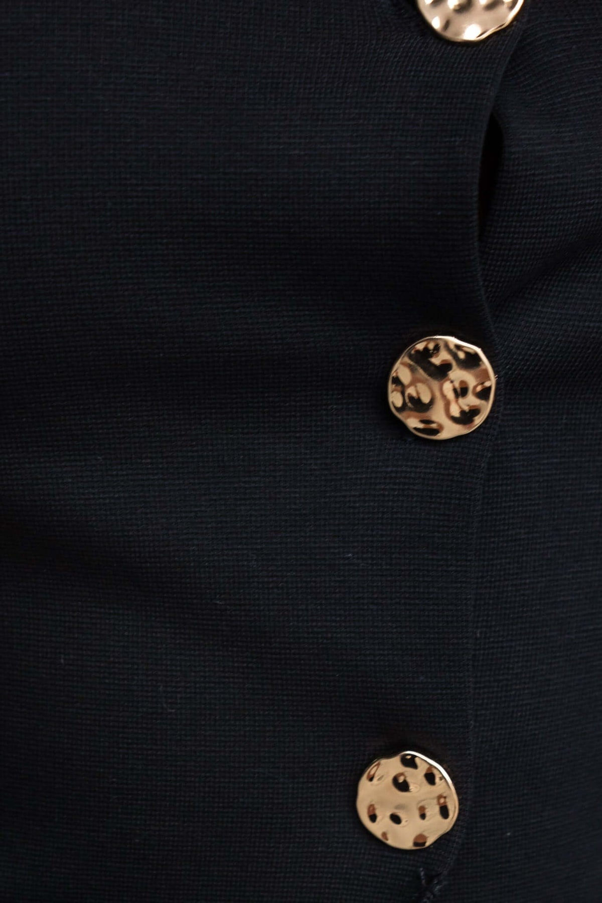 Close-up of the Summit Midi Skirt featuring stylish gold buttons on a black fabric.