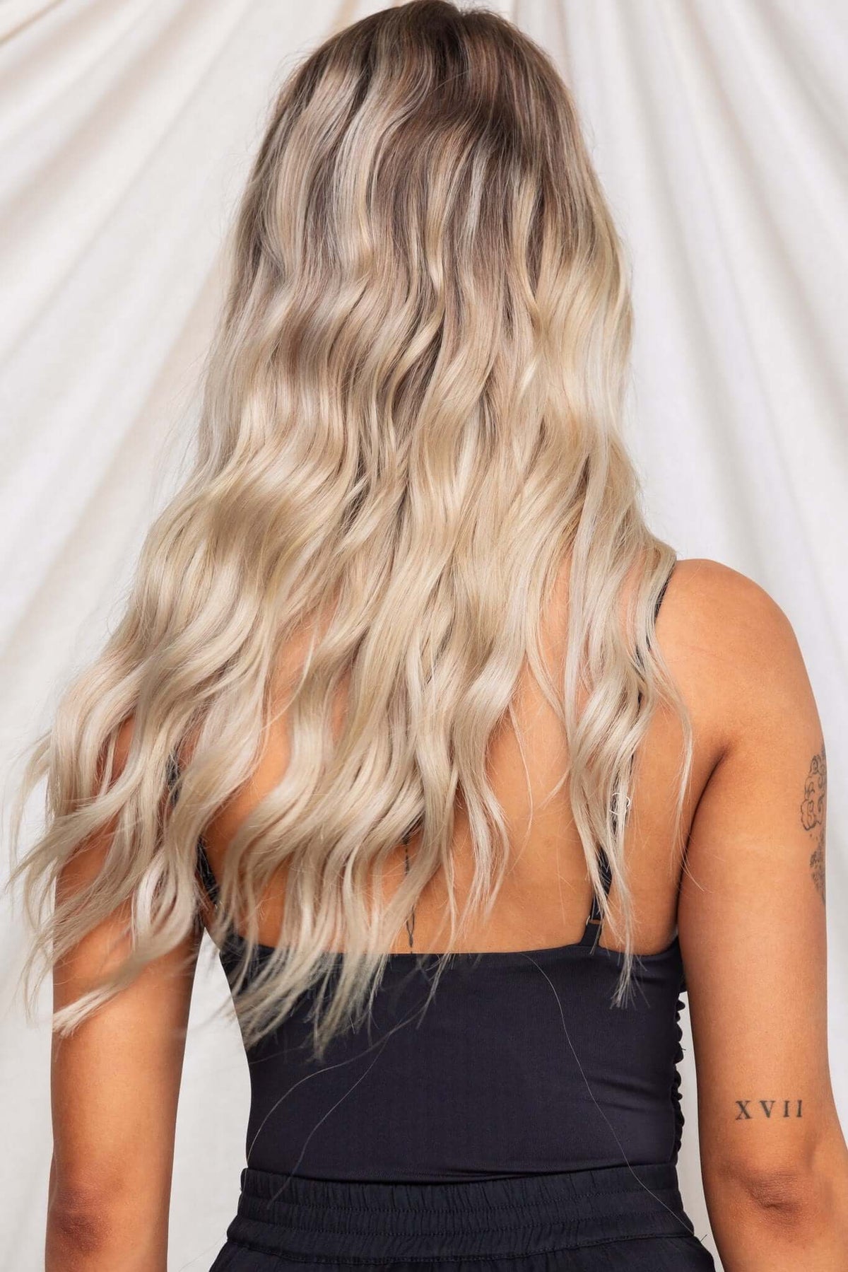 Back view of a model wearing the Oskar Bodysuit, showcasing wavy blonde hair and adjustable straps.