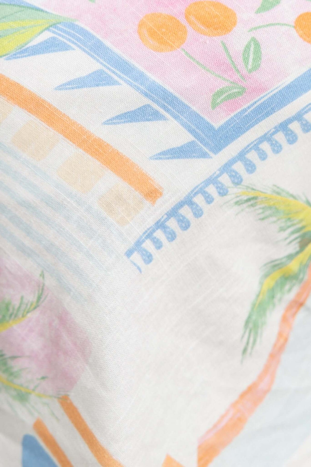 Colorful fabric pattern featuring pastel shades, palm leaves, and floral designs, ideal for casual clothing like shorts.