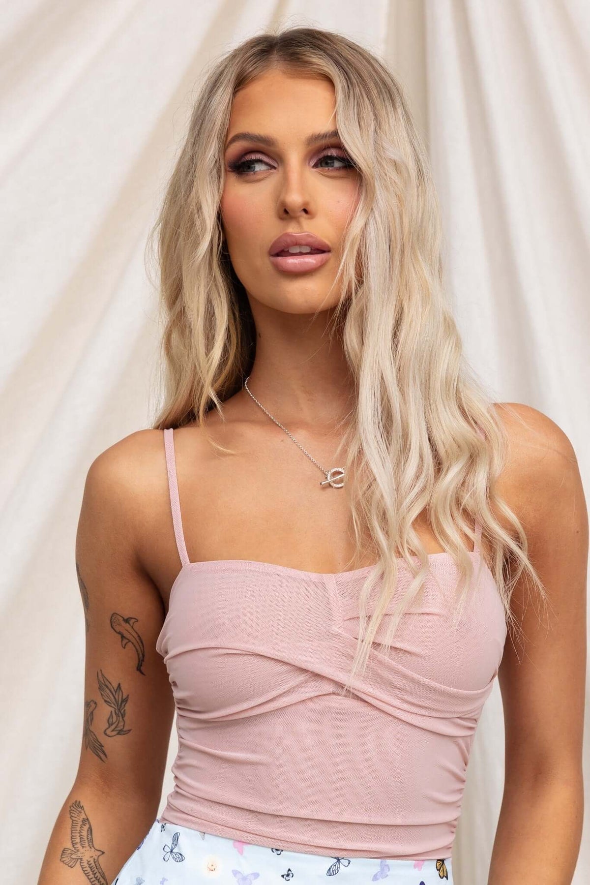 Model wearing a pink Kiton bodysuit with adjustable straps and soft mesh fabric, showcasing a stylish summer look.